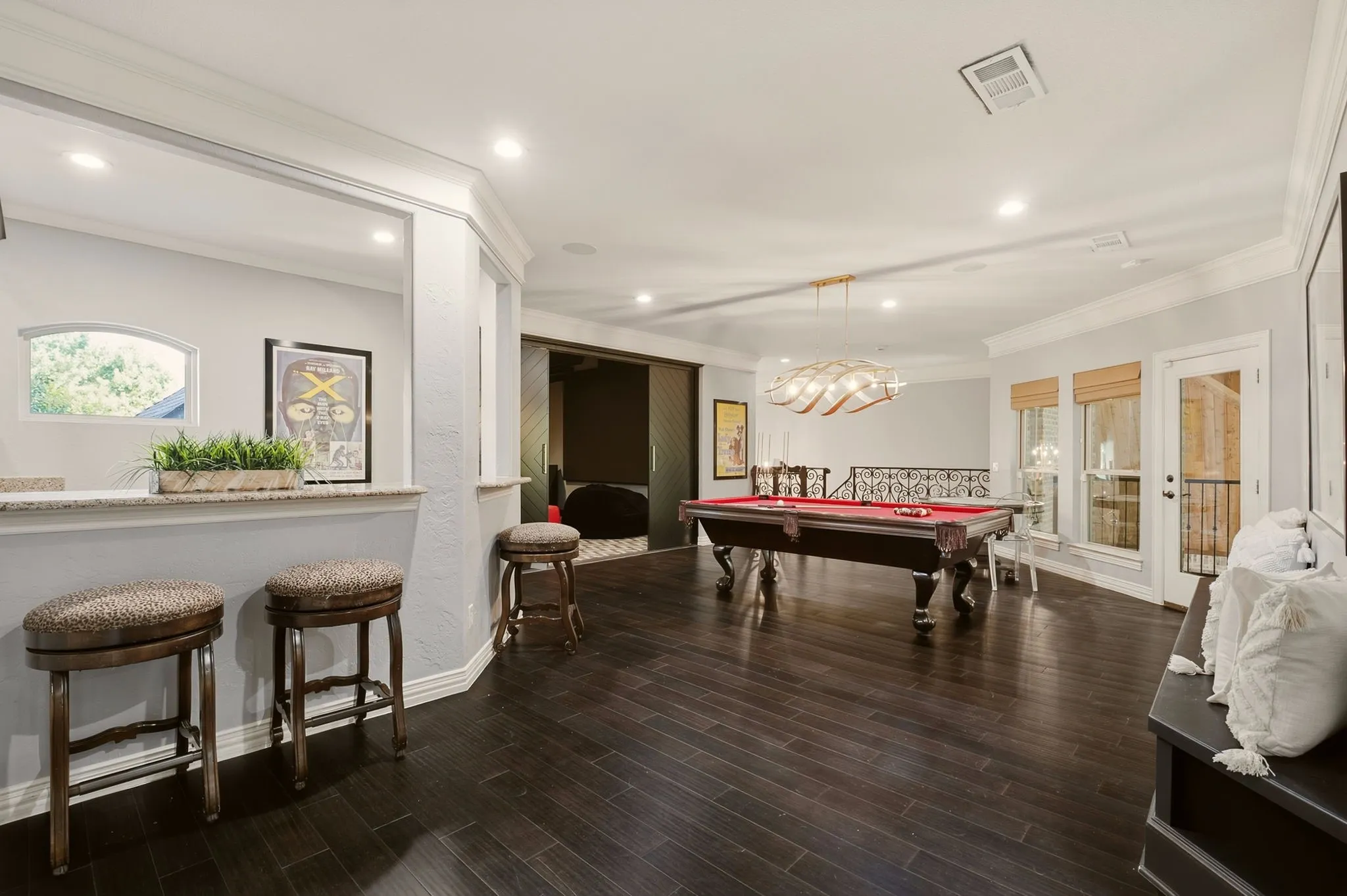 The second-floor game room is designed for elevated entertaining, featuring sleek, dark-toned engineered wood flooring and a custom built-in bench with integrated storage.