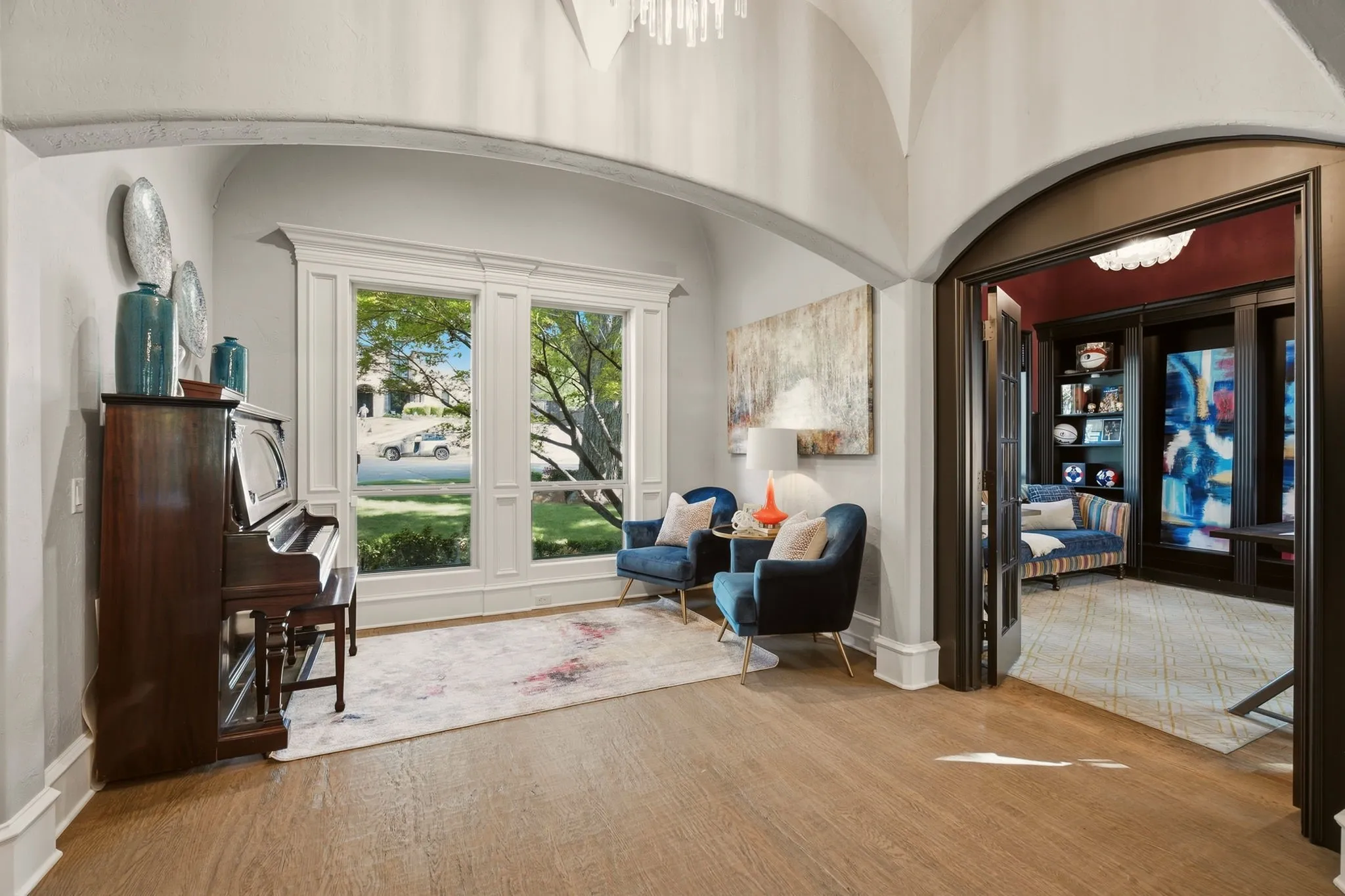 An elegant arched entryway opens to a versatile bonus space, perfectly suited for a piano room, sitting area, or quiet retreat to read and enjoy a cup of coffee. Two gorgeous windows overlook the front grounds, beautifully framed by intricate molding and detailed millwork.