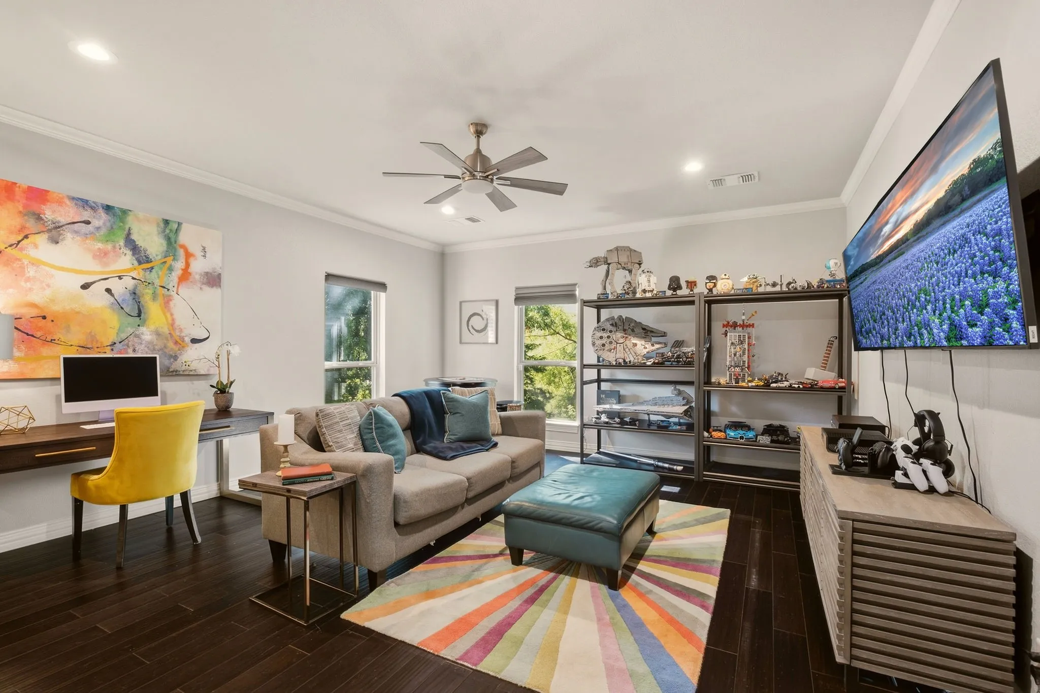 The light and bright oversized family room or second game room offers a welcoming setting for everyday relaxation and gathering, featuring warm wood floors, crown molding, and a new ceiling fan.
