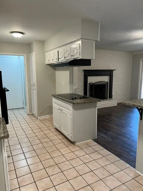 Kitchen featuring tile flooring, white cabinetry, and stone-finish countertops