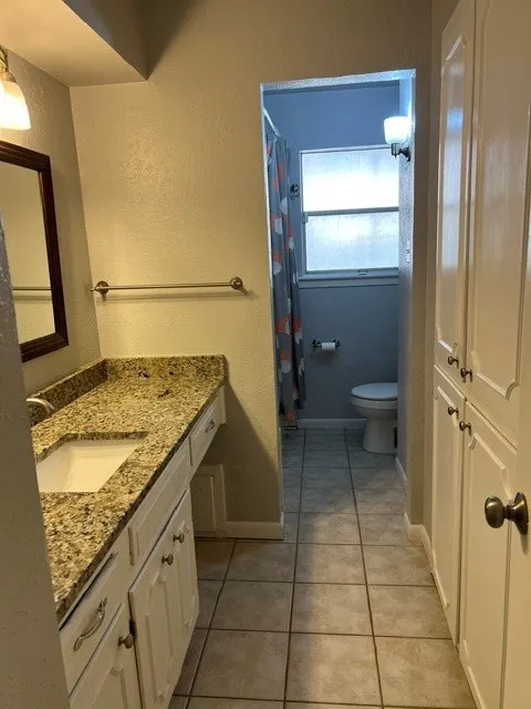 Bathroom featuring a vanity with an integrated sink, a speckled countertop, and white cabinetry