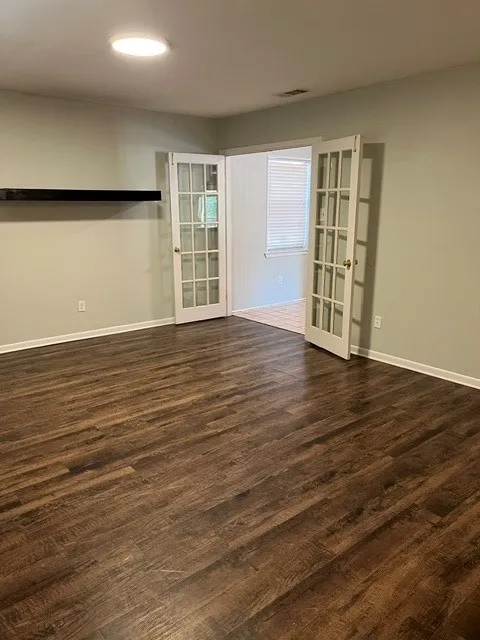 Wood-finish flooring, recessed ceiling lighting, French doors, and a built-in wall shelf