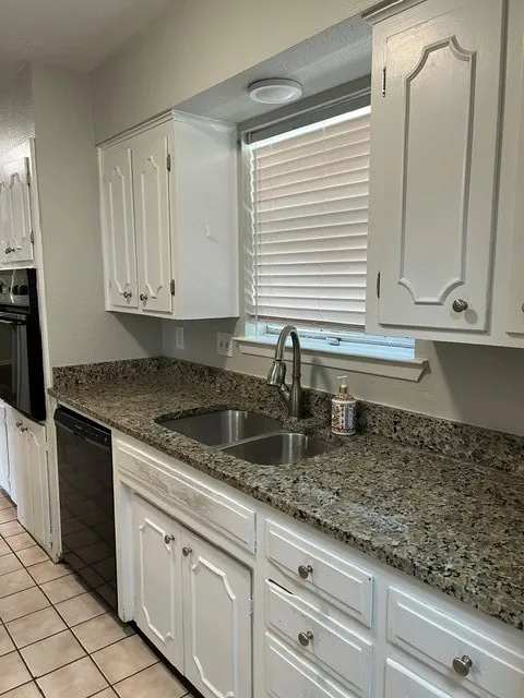 Kitchen featuring white cabinetry, a dual-basin stainless steel sink, a pull-down faucet, and speckled countertops