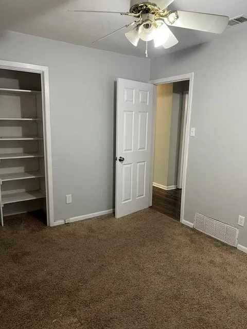 Plush carpet flooring, neutral wall tones, and a ceiling fan with integrated lighting