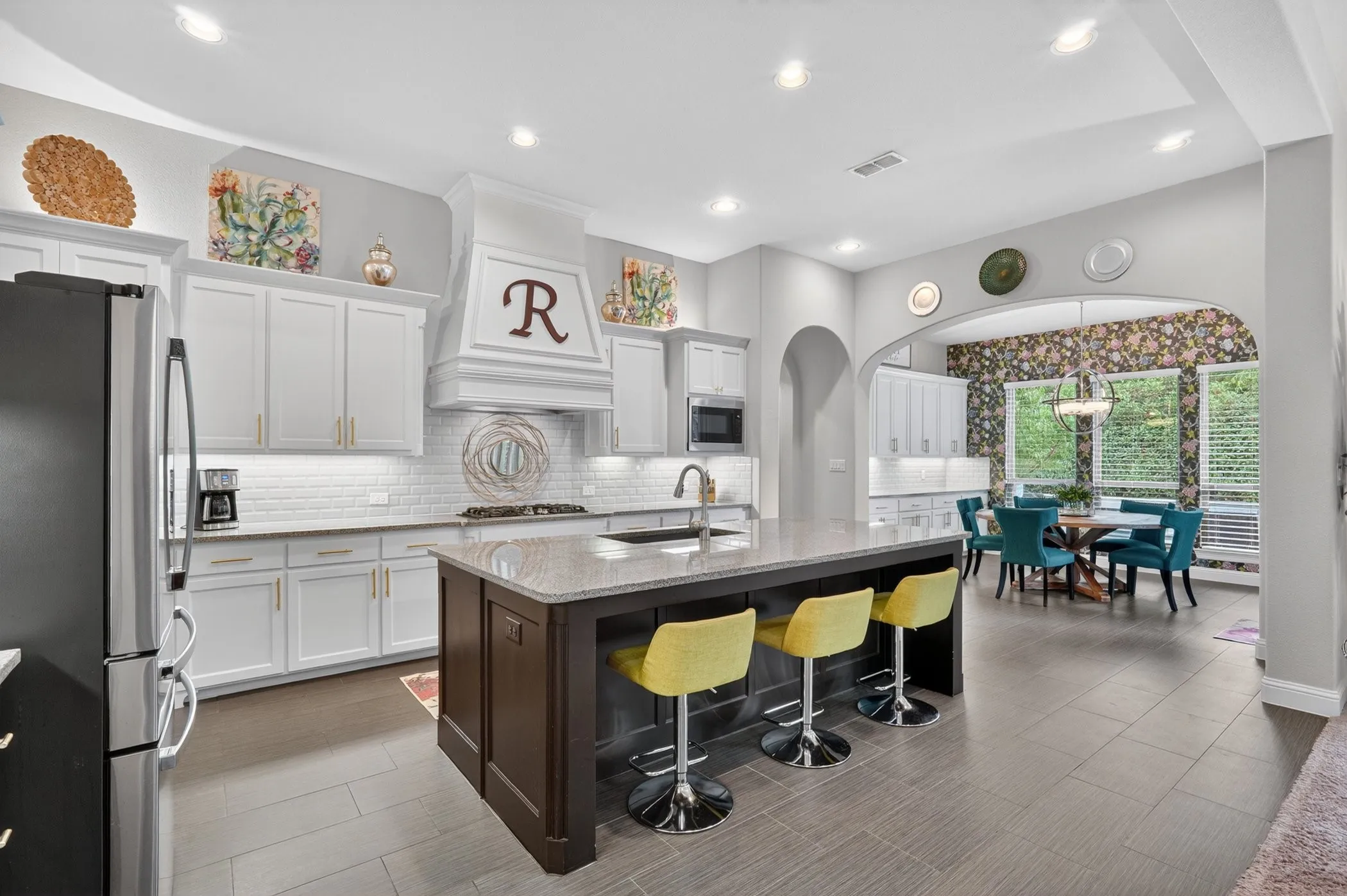 Spacious kitchen featuring an expansive center island with seating, white cabinetry, subway tile backsplash, and recessed lighting