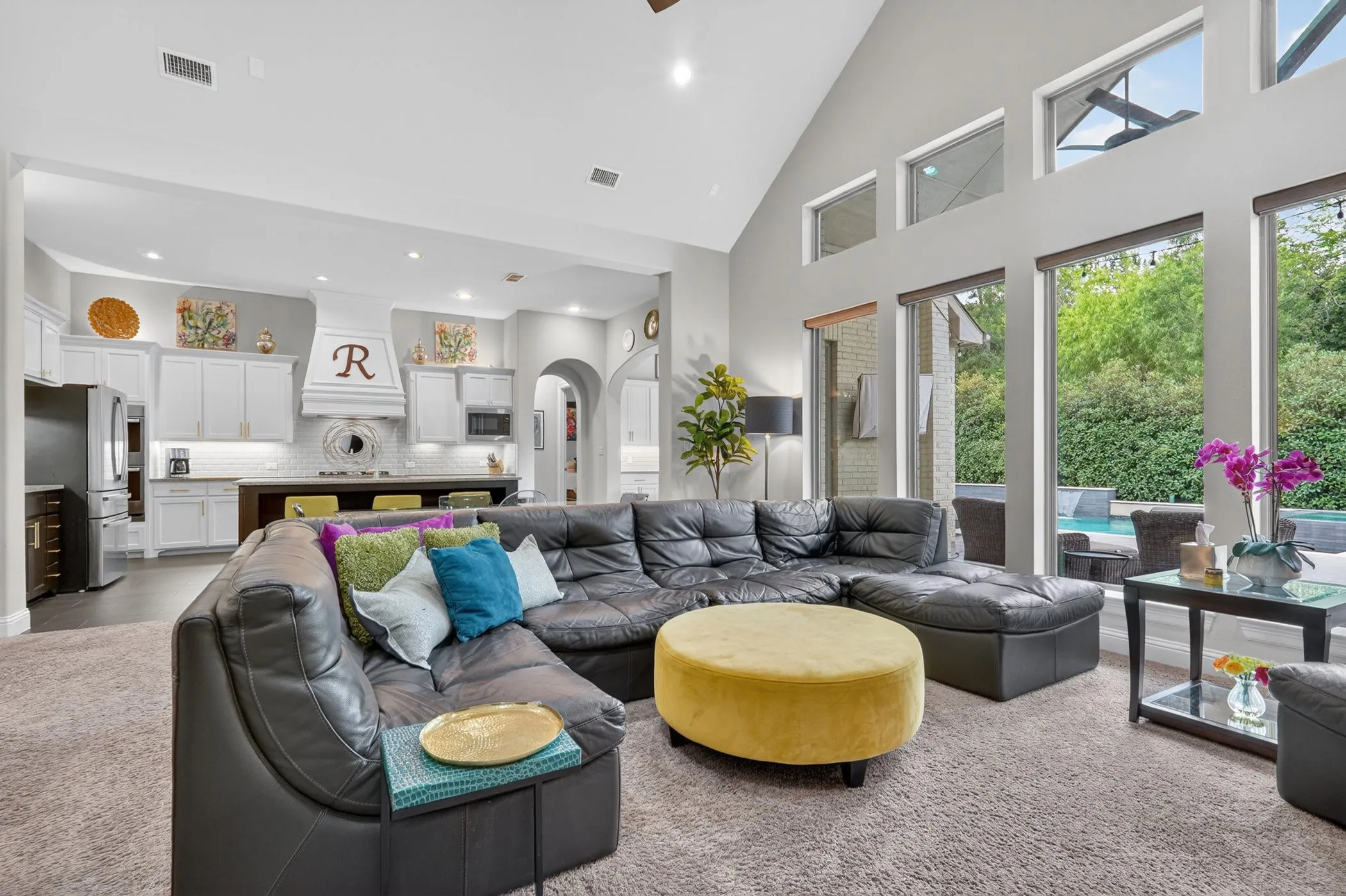 Open-concept living area with a vaulted ceiling and an abundance of natural light from floor-to-ceiling windows