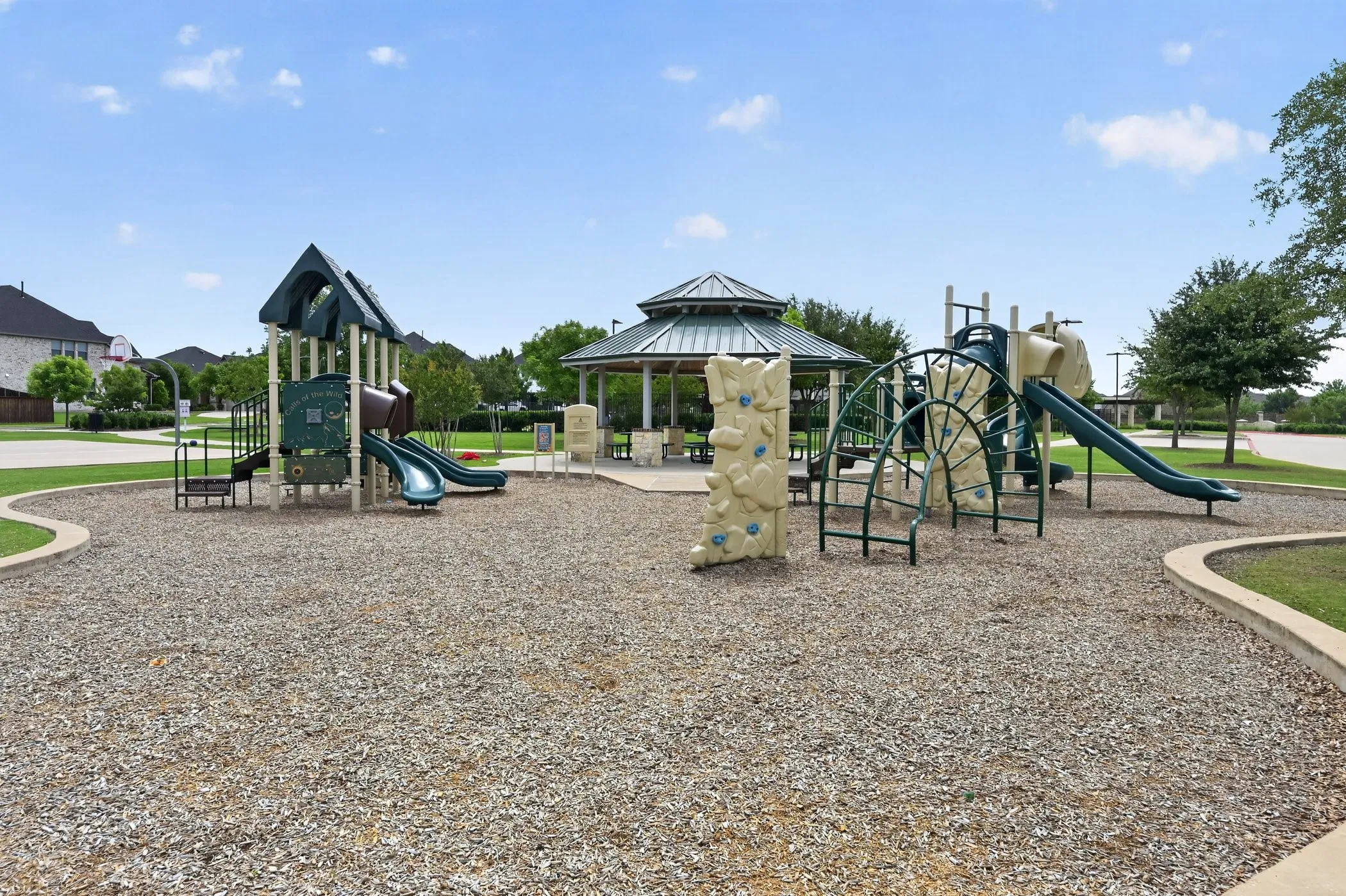 Community playground featuring multiple slides, climbing structures, and a shaded gazebo