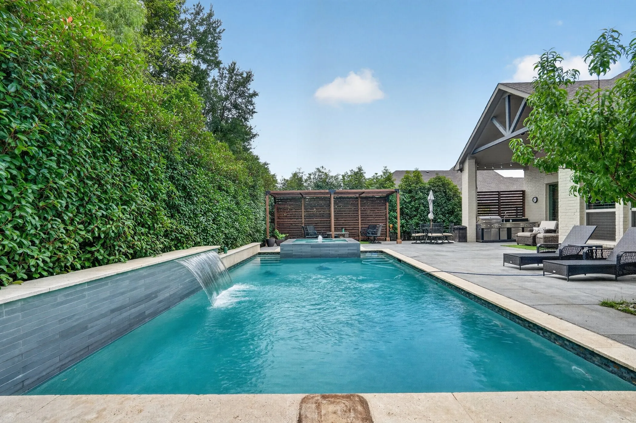 Rectangular swimming pool featuring a tiled waterfall and integrated hot tub