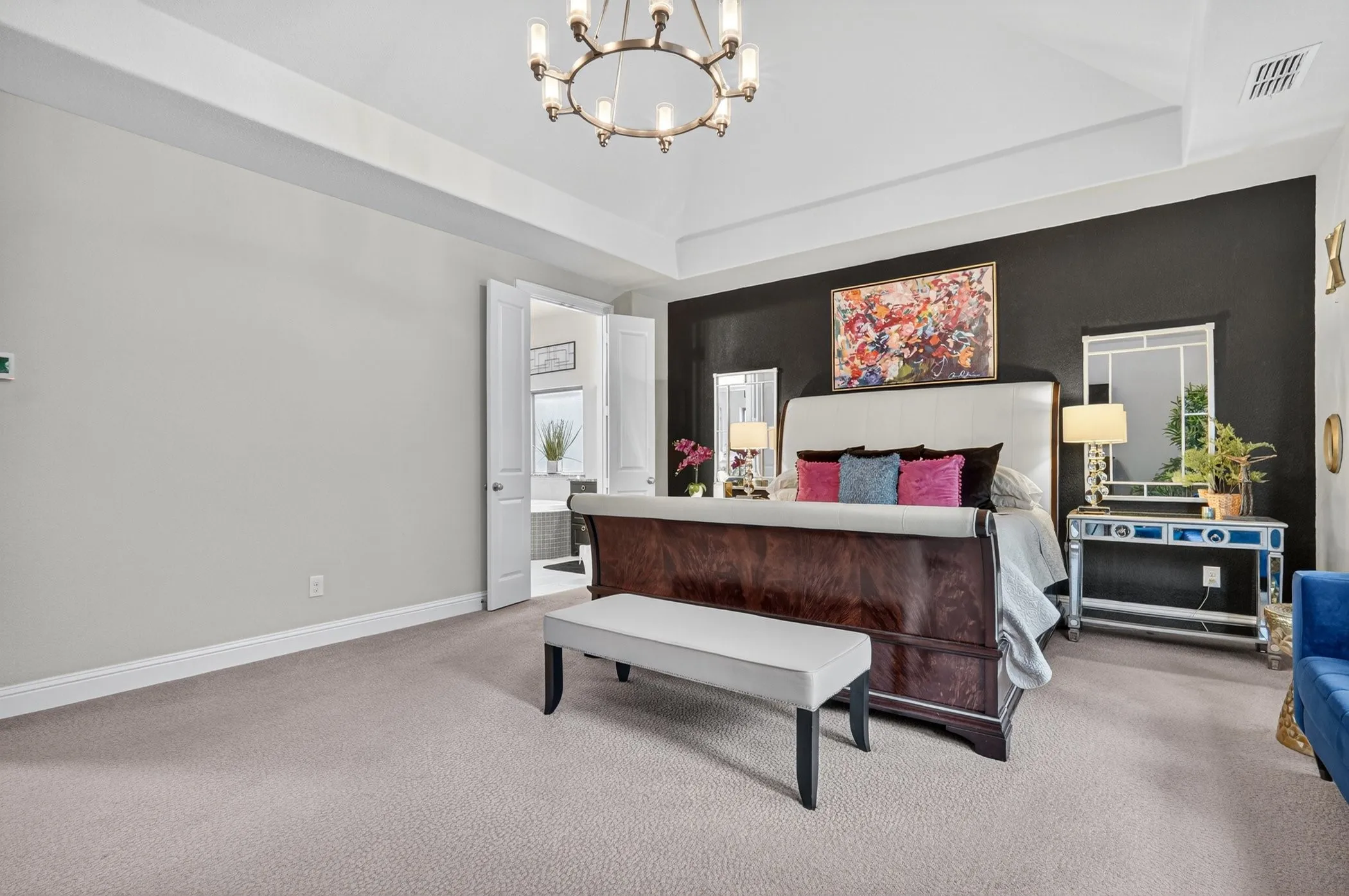 Spacious sleeping area featuring carpet flooring, a vaulted ceiling, and a prominent dark accent wall