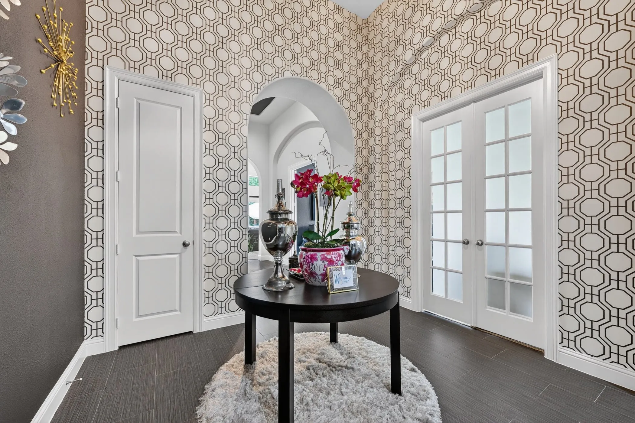 Foyer featuring patterned wall coverings, dark wood-finish flooring, an arched doorway, and double French doors