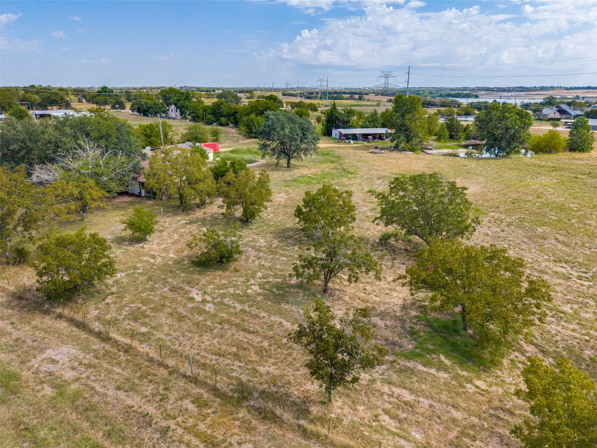 Expansive undeveloped land featuring mature trees and a distant water body