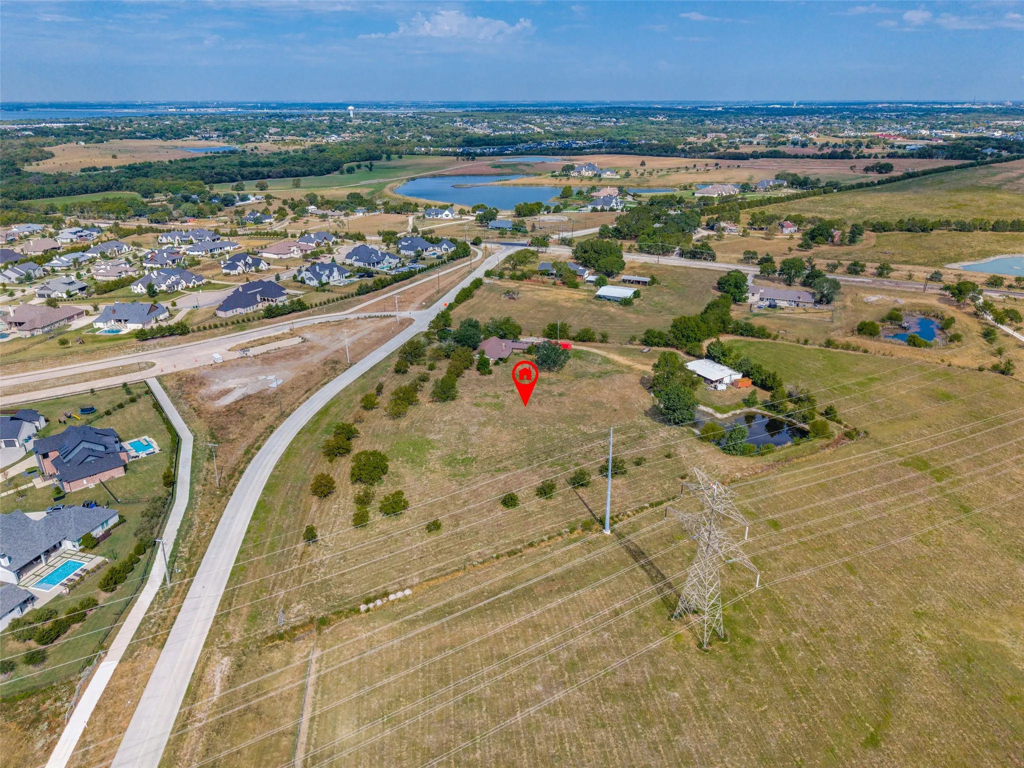 Expansive land parcel featuring open fields, scattered mature trees, and a visible pond