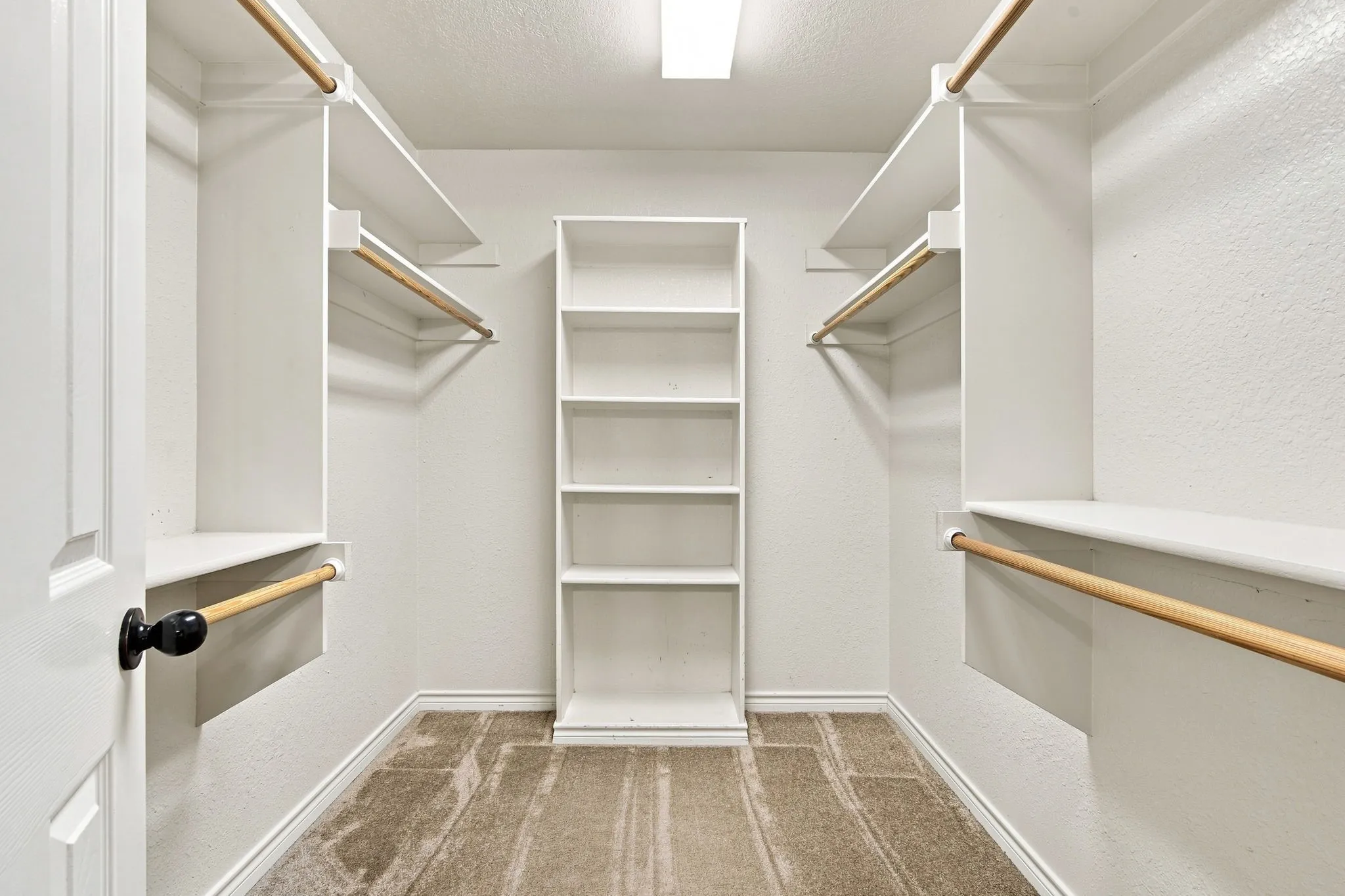Impressively organized walk-in closet with custom shelving, integrated hanging rods, and built-in central storage.