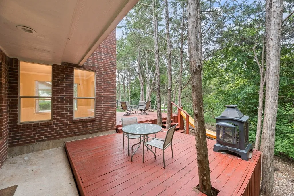 Multi-level wood deck with integrated trees and a brick exterior