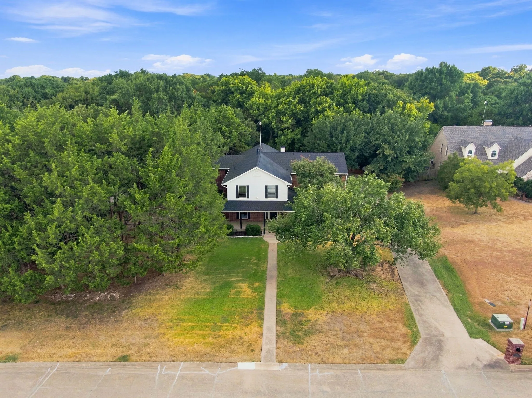 Treetop aerial view showcasing the home's gabled roofline nestled among mature, established trees for wonderful privacy and shade.