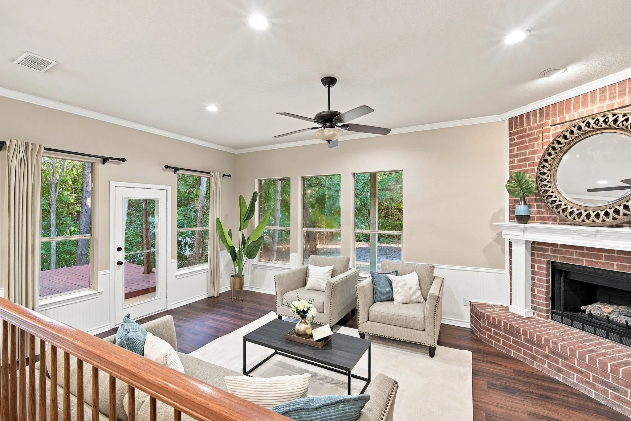 Charming sitting room with a vaulted ceiling, ceiling fan, cozy brick fireplace, and French doors opening to the backyard, a perfect spot to unwind.