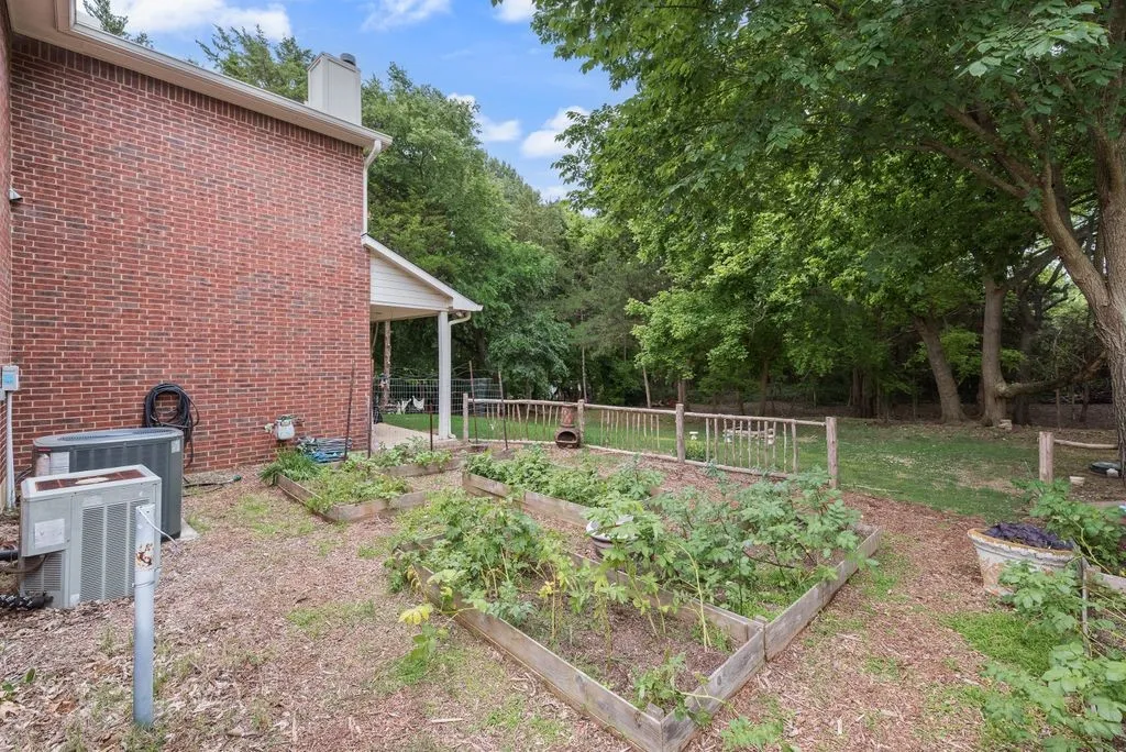 Raised garden beds and mature trees create a peaceful backyard setting with plenty of space to garden, relax, and enjoy the outdoors.