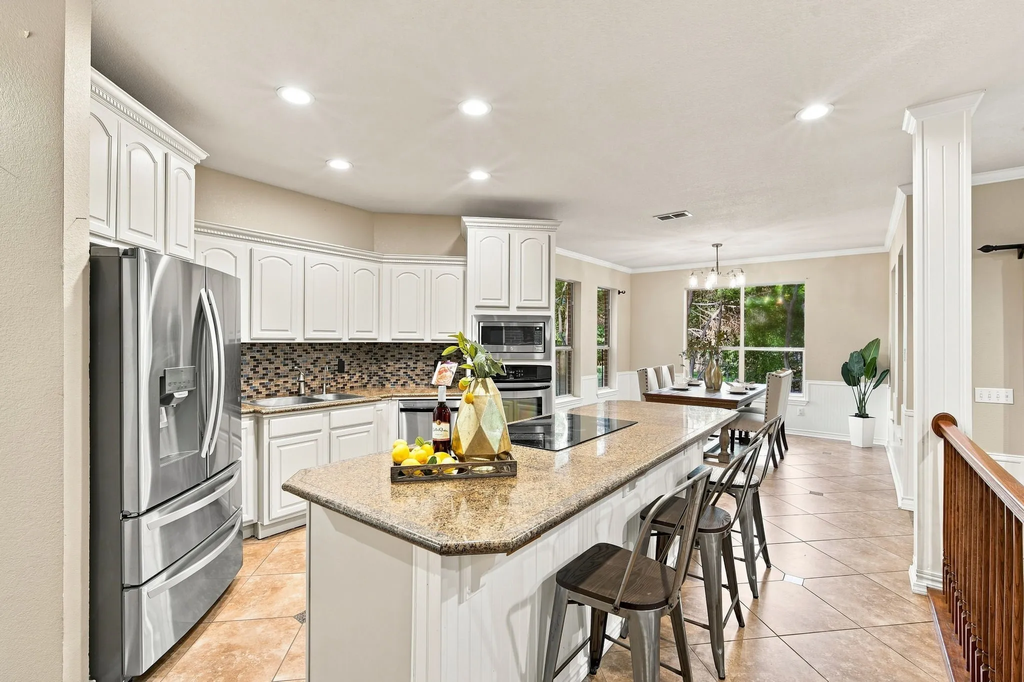 Beautifully appointed kitchen with crisp white cabinetry, a spacious island with a cooktop, and a stylish tile backsplash.