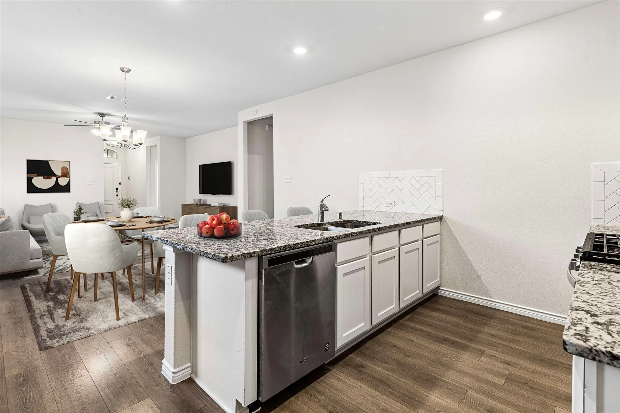 Kitchen island with granite countertops, stainless steel dishwasher, and white shaker-style cabinetry