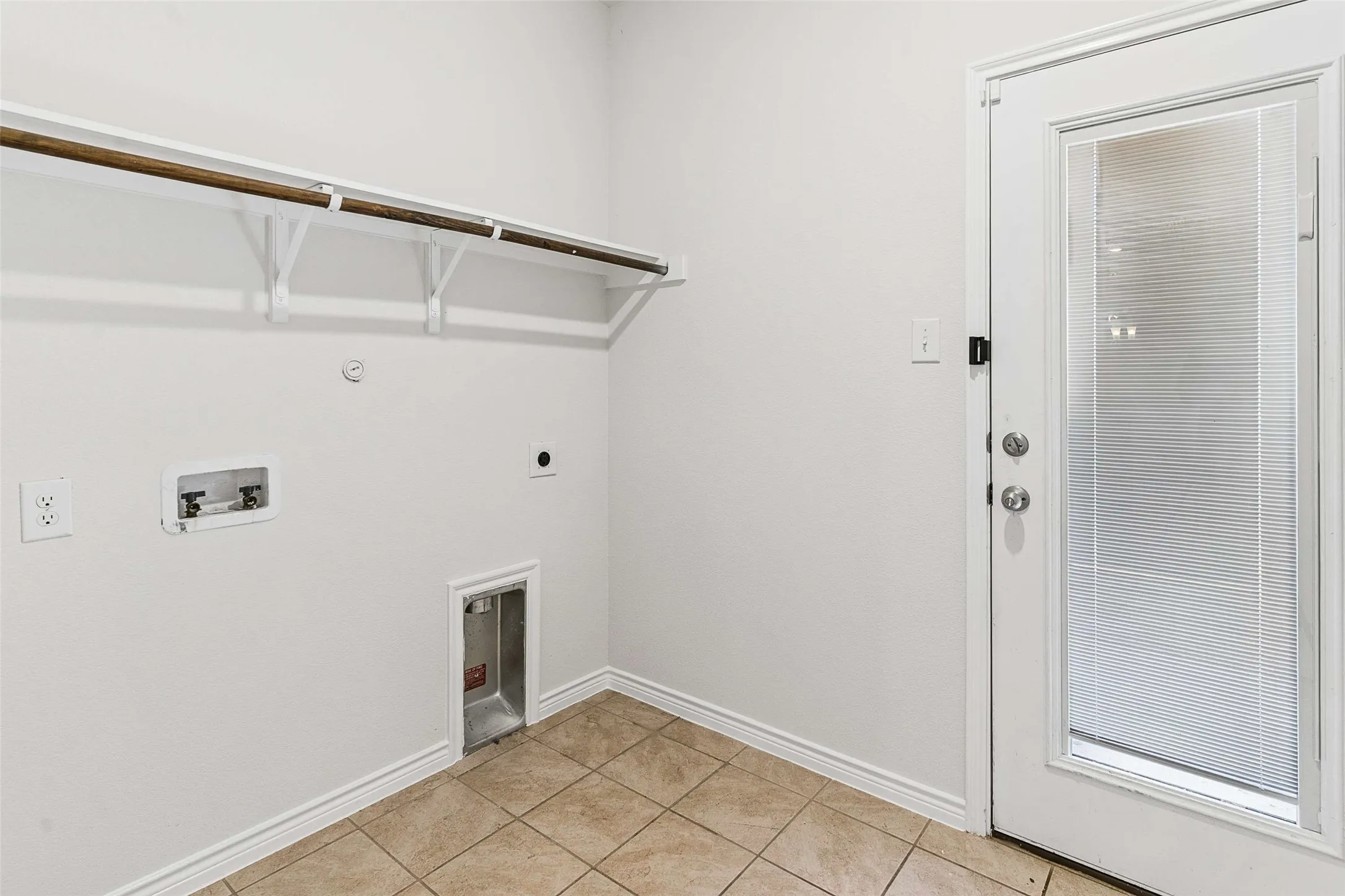 Laundry area featuring a built-in hanging rod, wall-mounted electrical outlets, and a utility box
