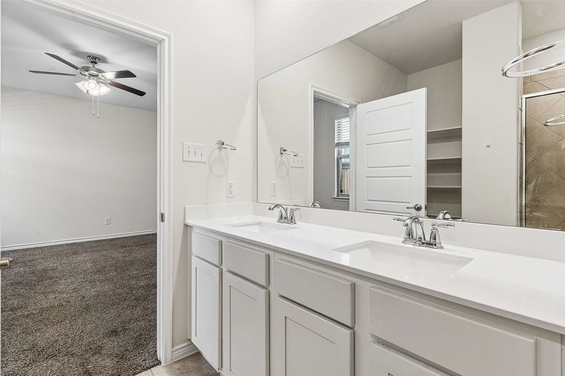Dual vanity with white cabinetry and integrated sinks, wide mirror, and chrome fixtures