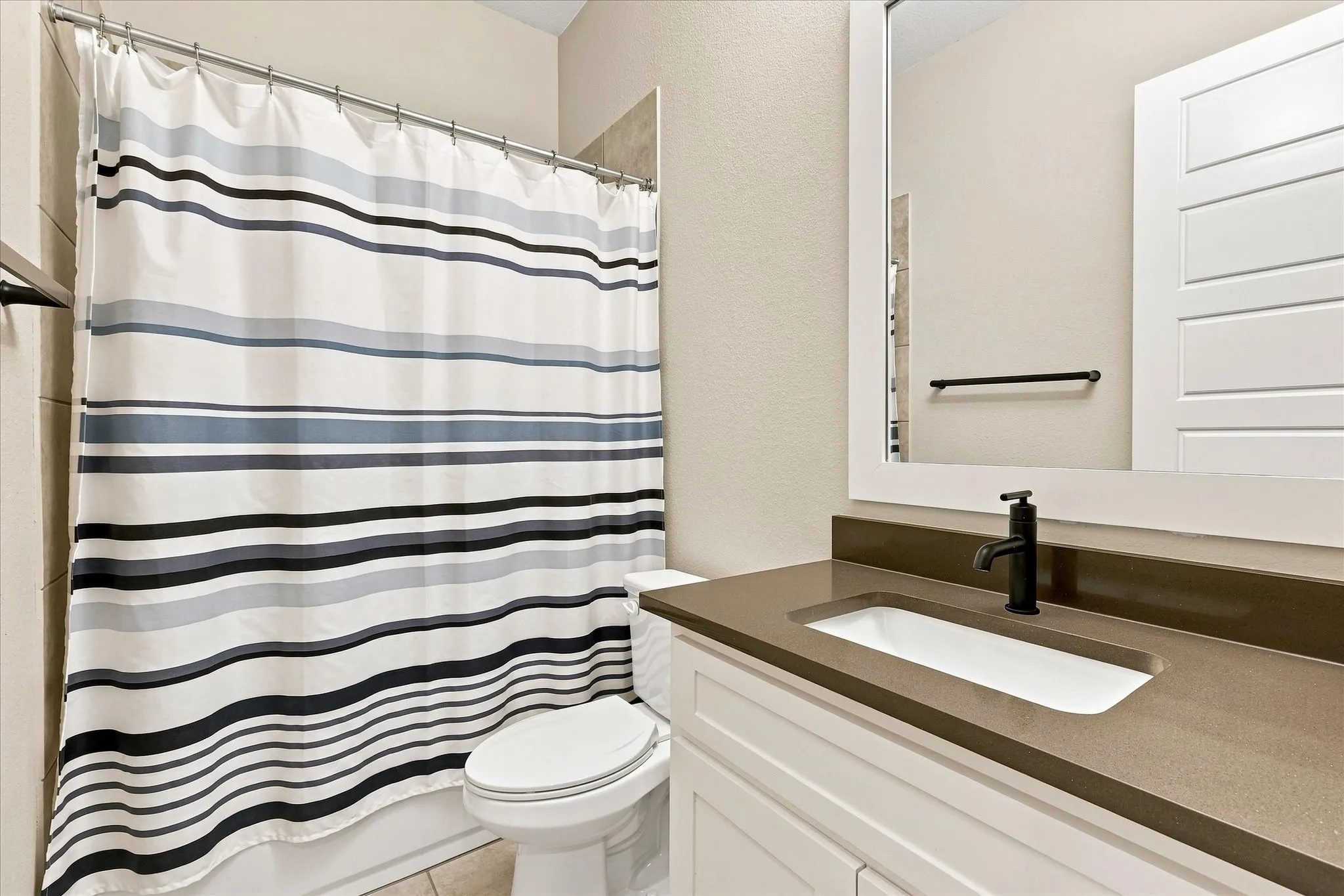 White vanity with a brown countertop, undermount sink, and matte black faucet
