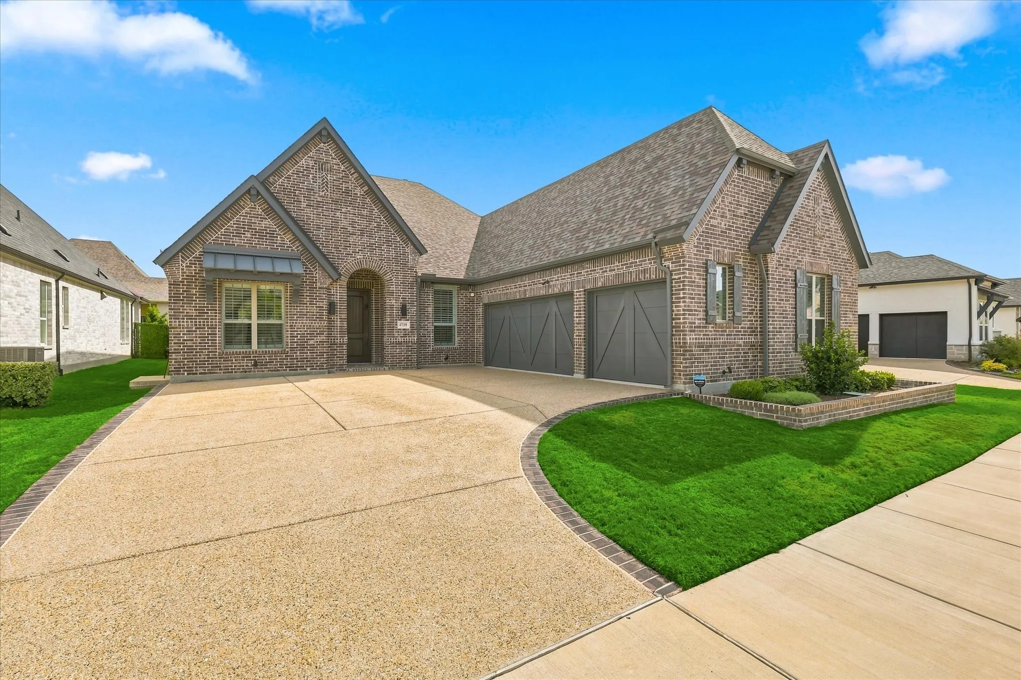 Brick exterior with a gabled roofline, multiple windows, and a three-car garage