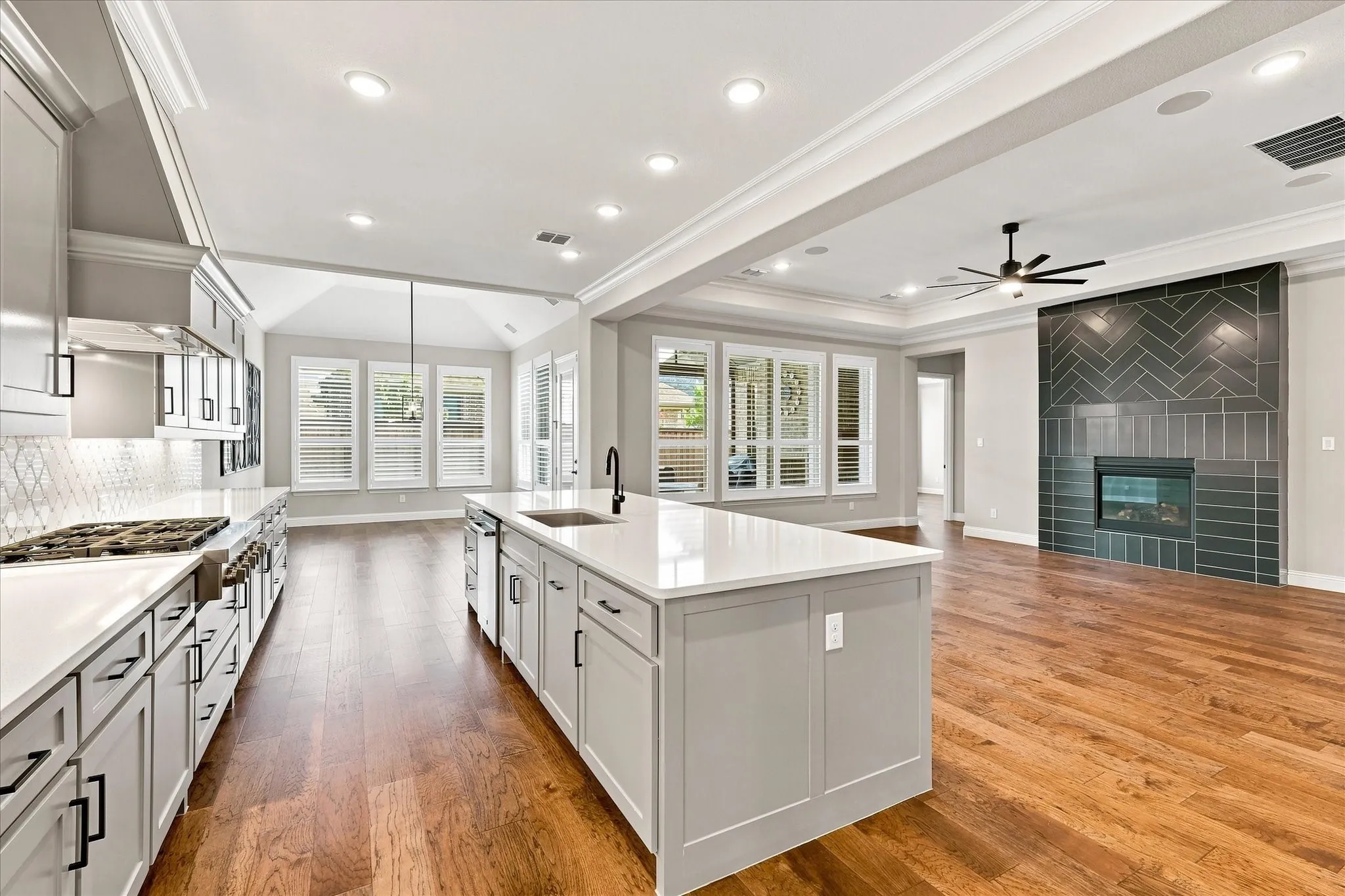 Gourmet kitchen with stainless steel appliances, quartz countertops, a large island, and wood-finish flooring