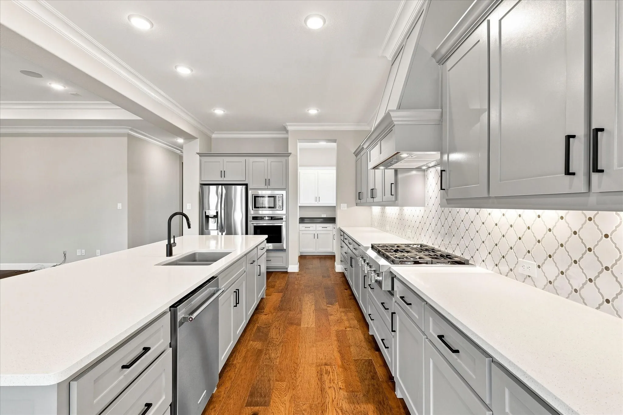 Gourmet kitchen featuring light gray cabinetry, white countertops, built-in stainless steel appliances, and wood-finish flooring