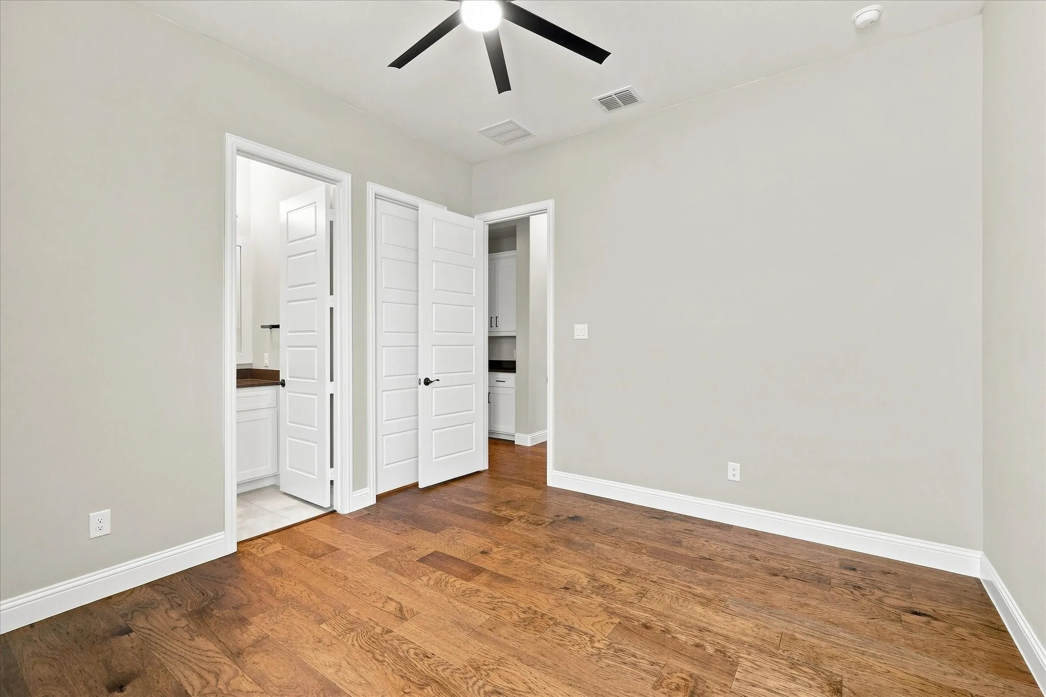 Hardwood flooring, painted walls, modern ceiling fan, white trim, and a white paneled door