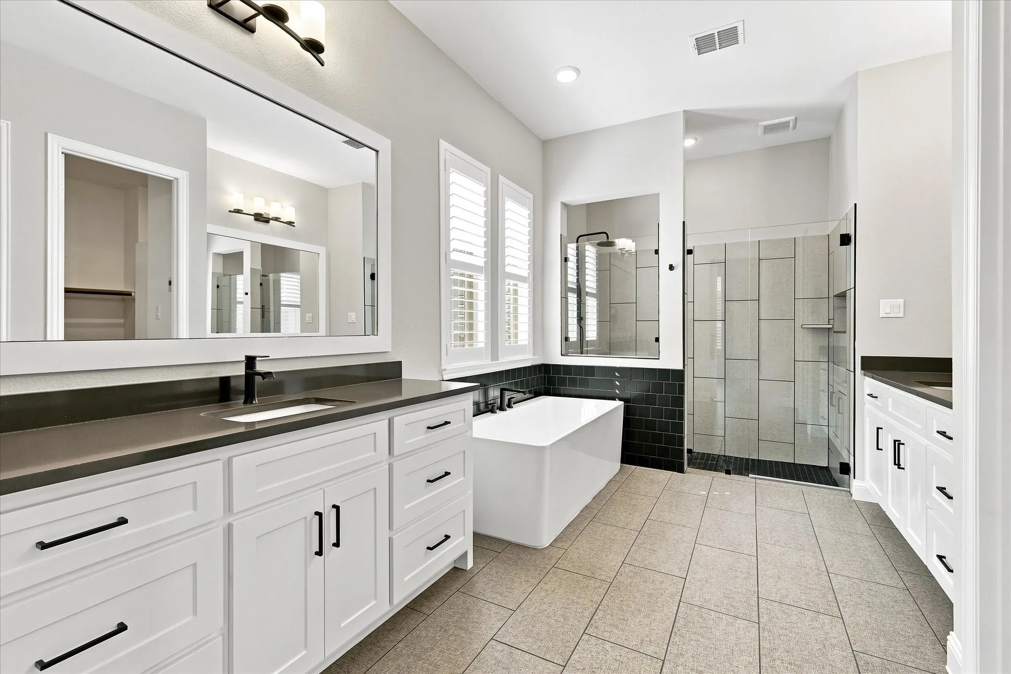 Dual vanity with white cabinetry, matte black hardware, and dark countertops