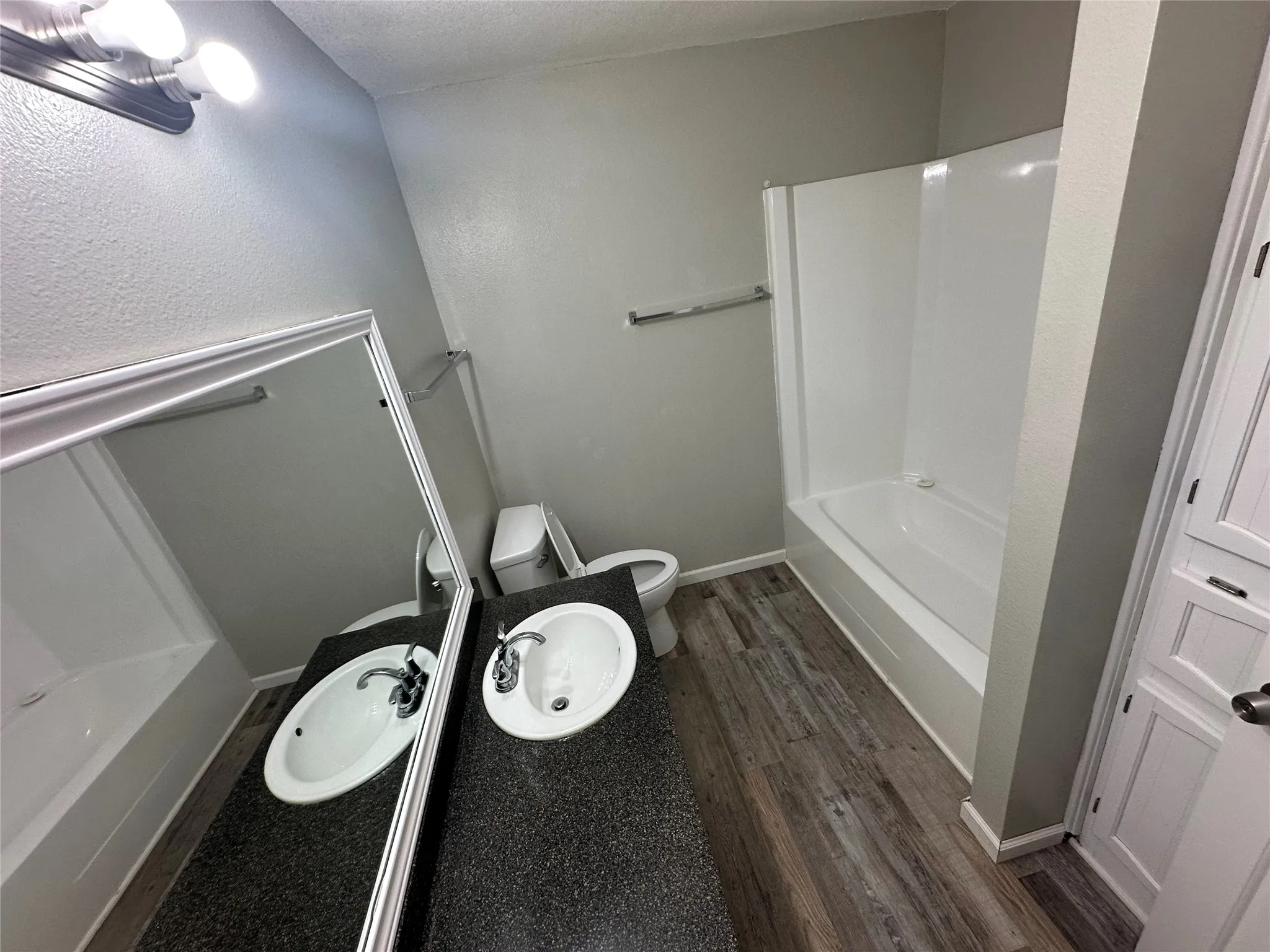 Vanity with dual integrated sinks, speckled countertop, and large wall-mounted mirror