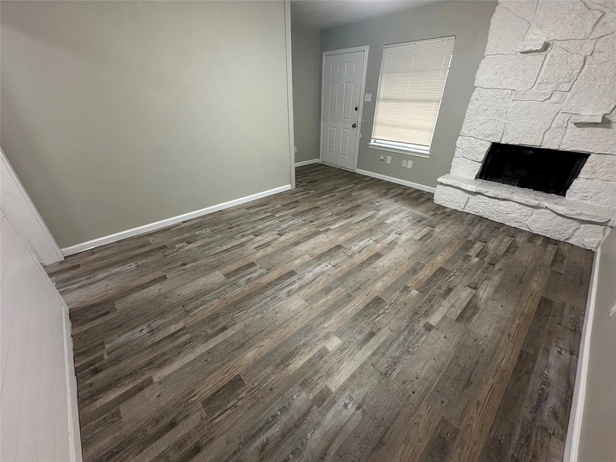 Wood-finish flooring, stone-clad fireplace, and painted interior walls