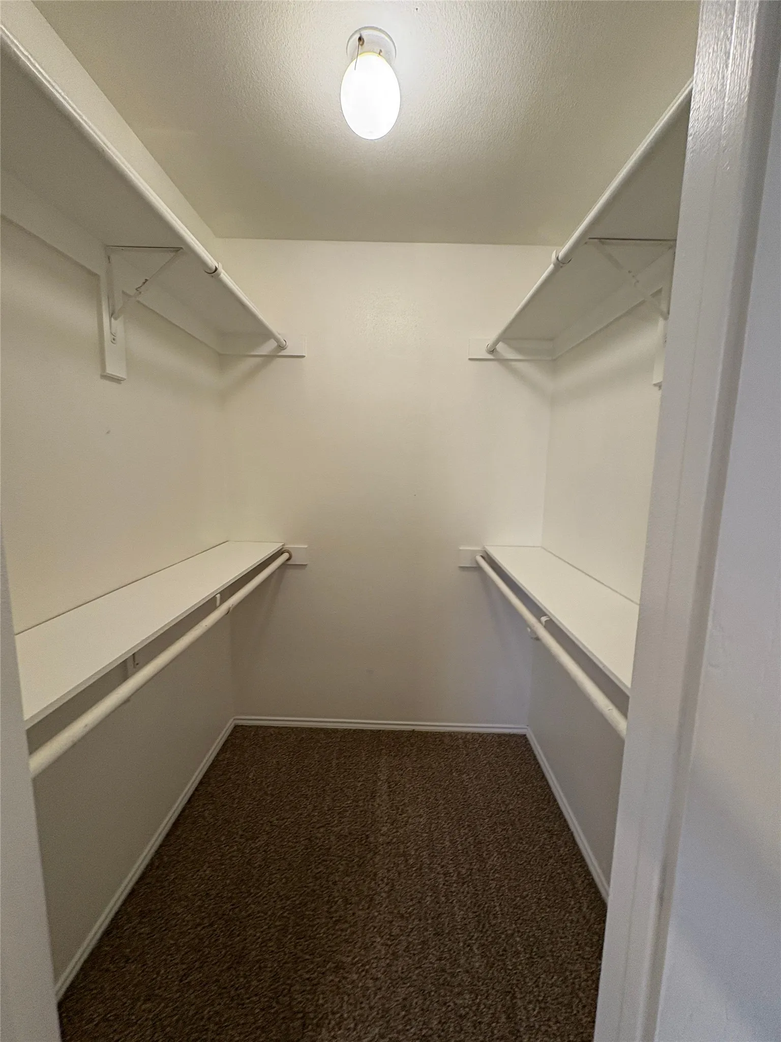 Walk-in closet with overhead lighting, dual shelving, and integrated hanging rods