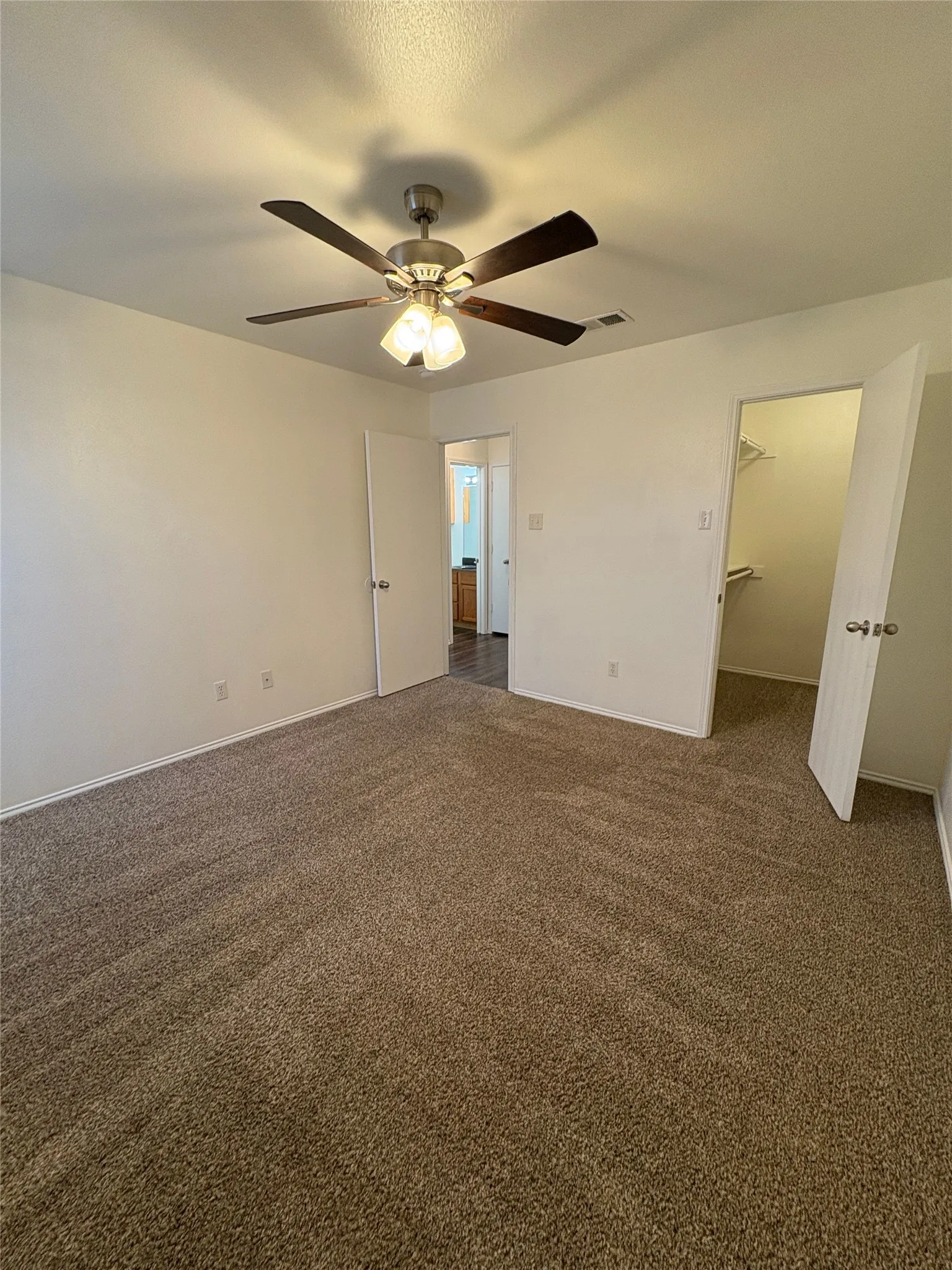 Spacious room with plush carpeting and a ceiling fan