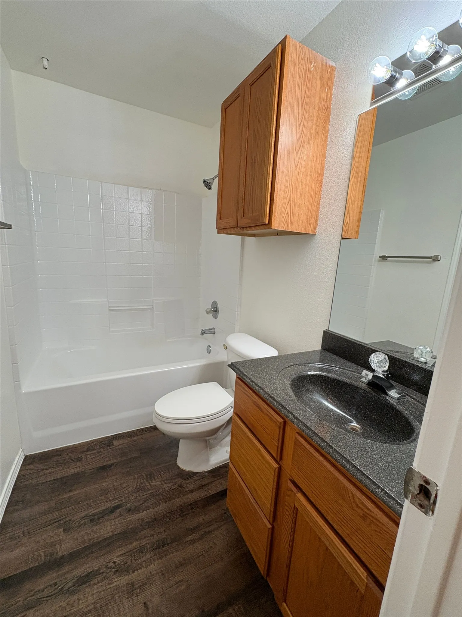 Wood-finish flooring with a white bathtub and toilet