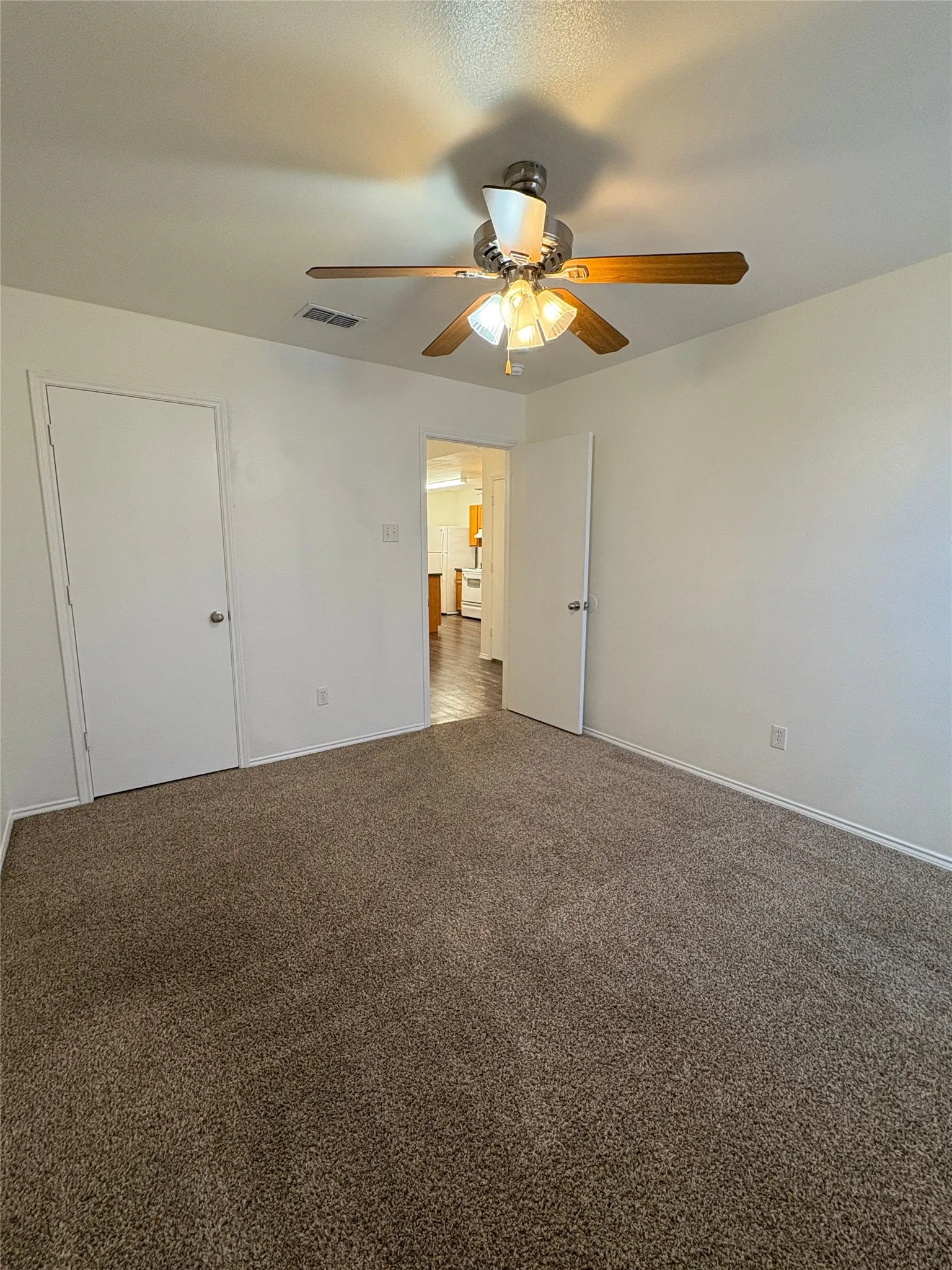 Carpeted flooring complemented by a ceiling fan with integrated lighting
