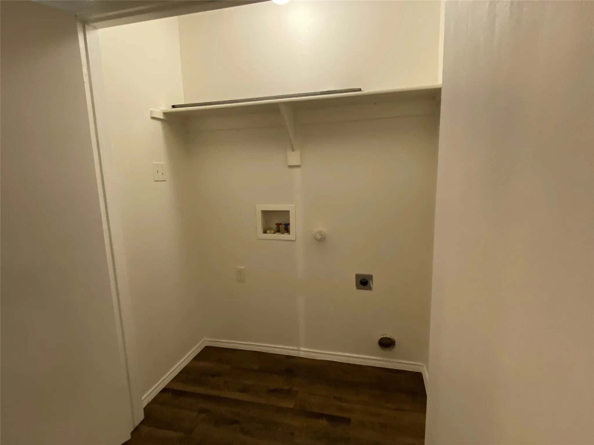 Utility closet featuring wood-finish flooring, built-in shelving, and appliance hookups