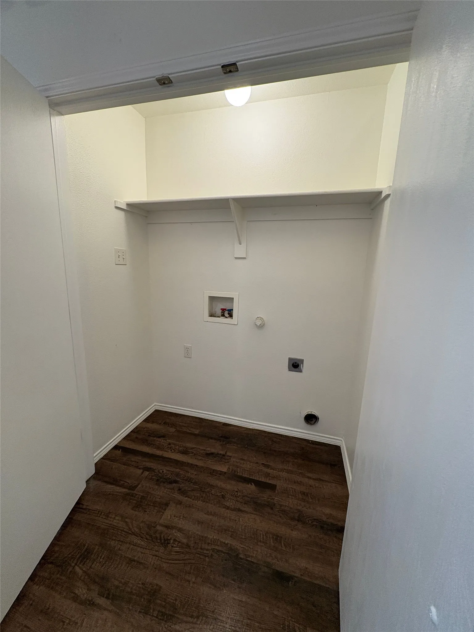 Dedicated laundry area featuring wood-finish flooring, white walls, and built-in shelving