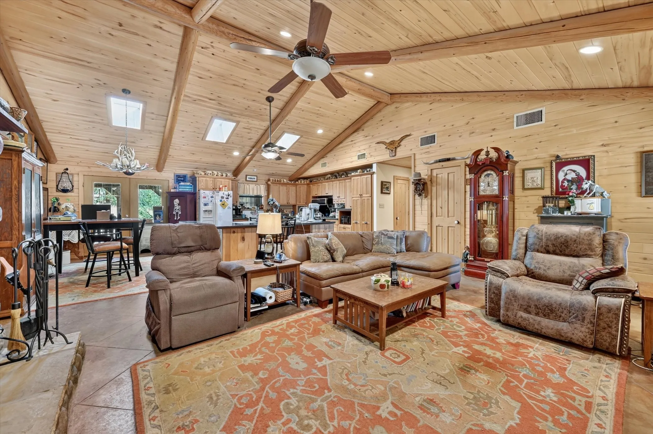 Vaulted wood-paneled ceiling with exposed beams, multiple skylights, and ceiling fans