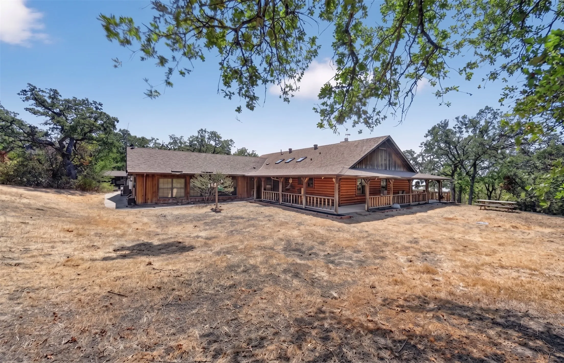 Log home exterior featuring a covered front porch, wood siding, and a shingle roof