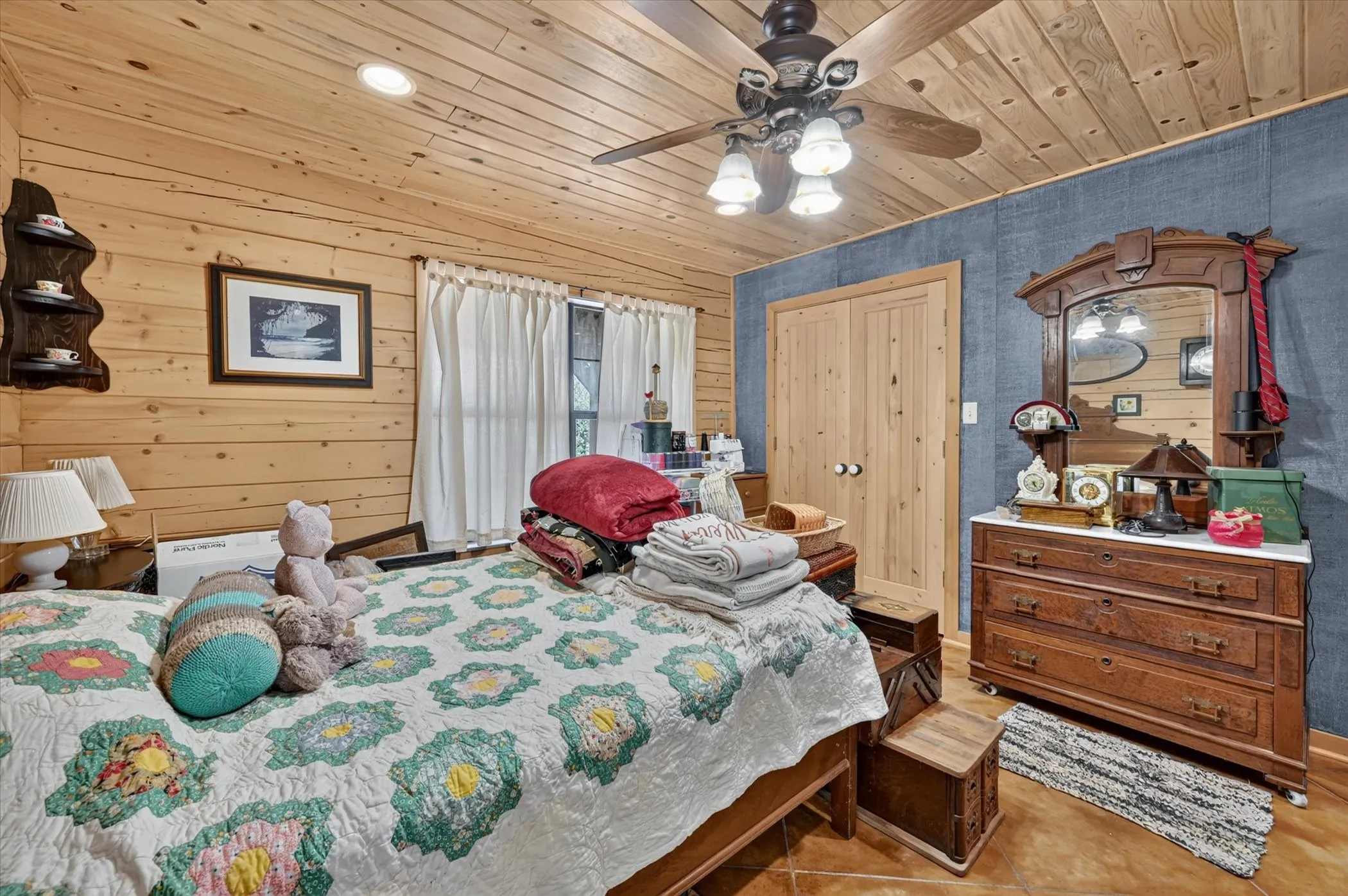 Wood-paneled walls and ceiling, ceiling fan with integrated lighting, wood-finish flooring, built-in dual-door closet, and window with privacy curtains
