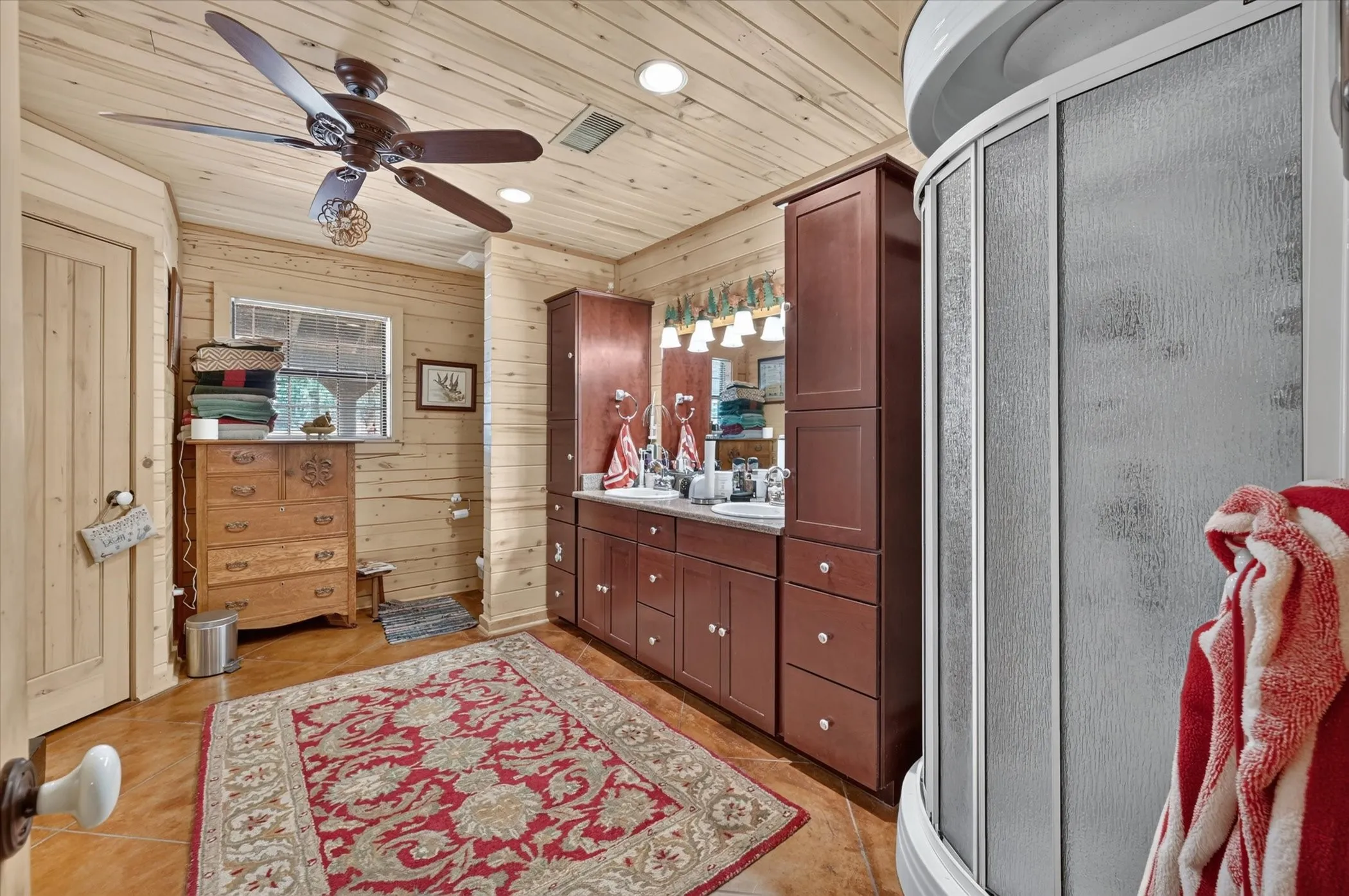 Wood-paneled walls and ceiling, dual vanity with integrated sinks, and a stand-alone shower enclosure