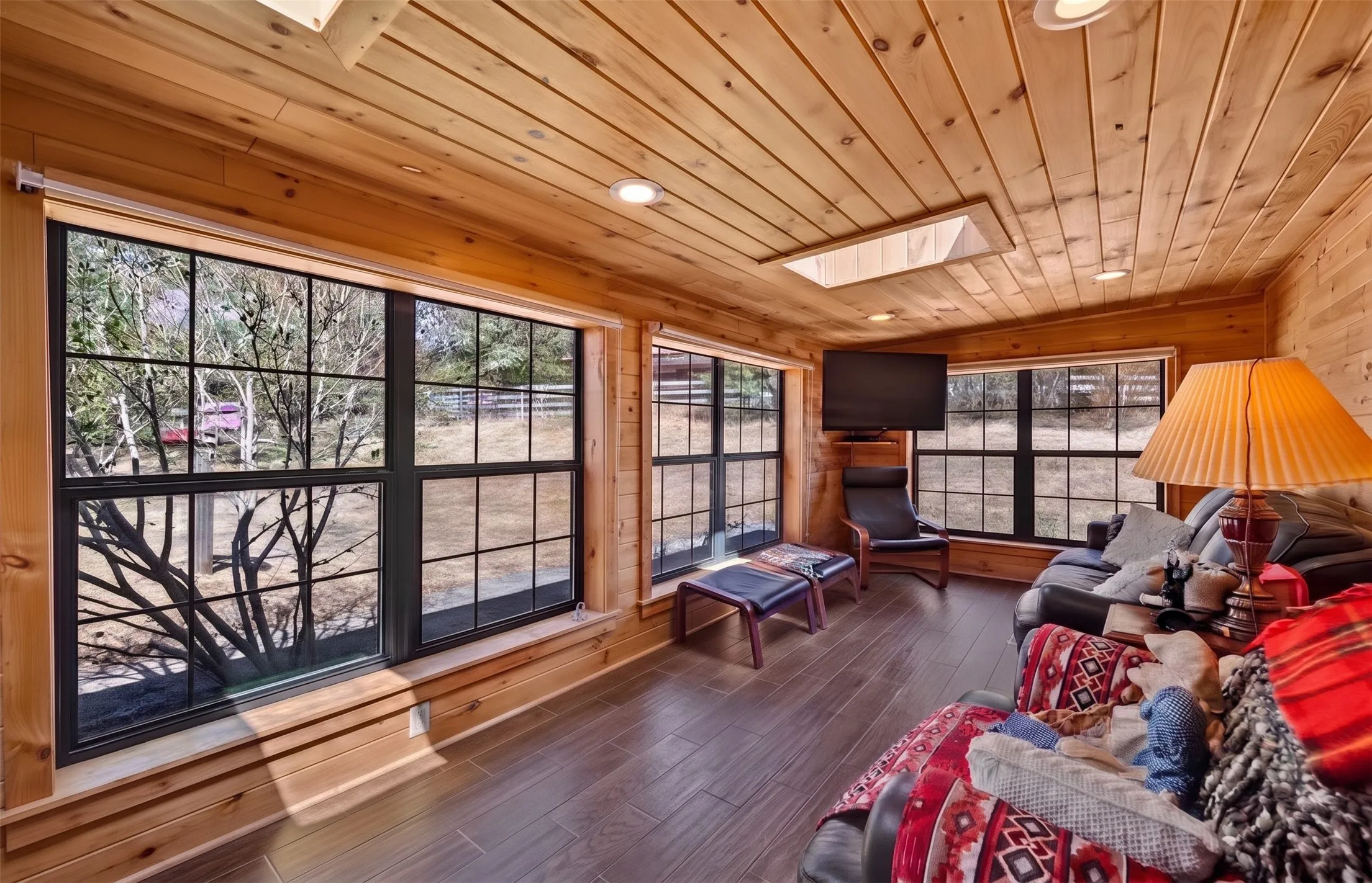 Wood-paneled walls and ceiling, skylight, recessed lighting, wood-finish flooring, and multiple window units