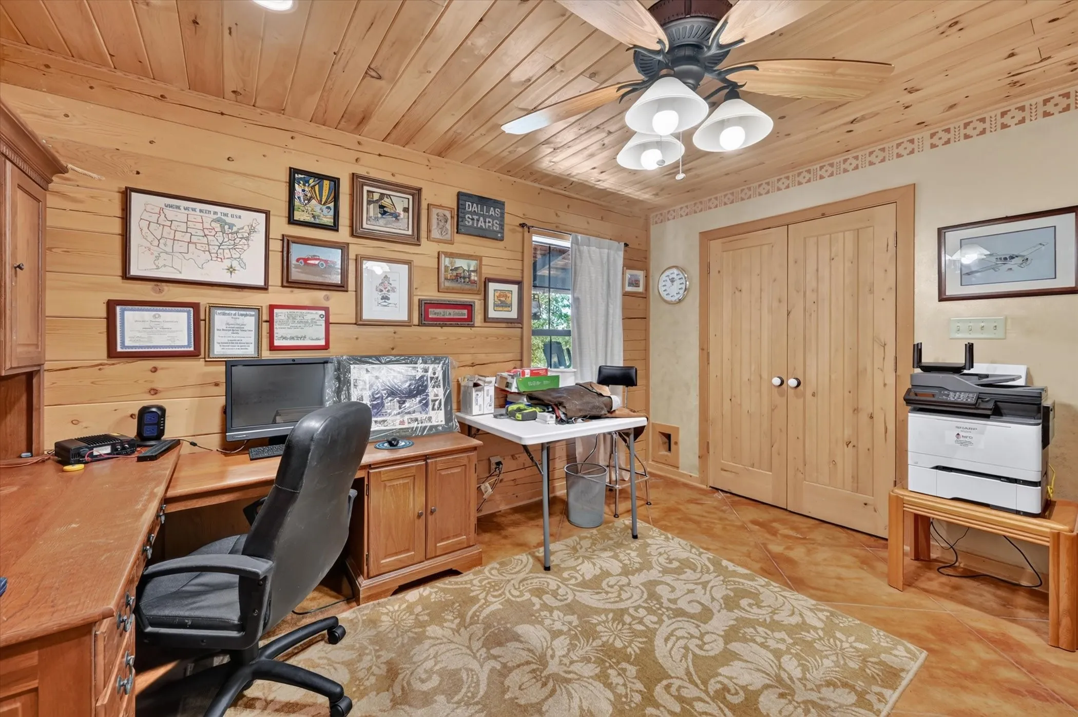 Wood-paneled walls and ceiling, wood-finish flooring, ceiling fan with integrated lighting, and built-in wood cabinetry