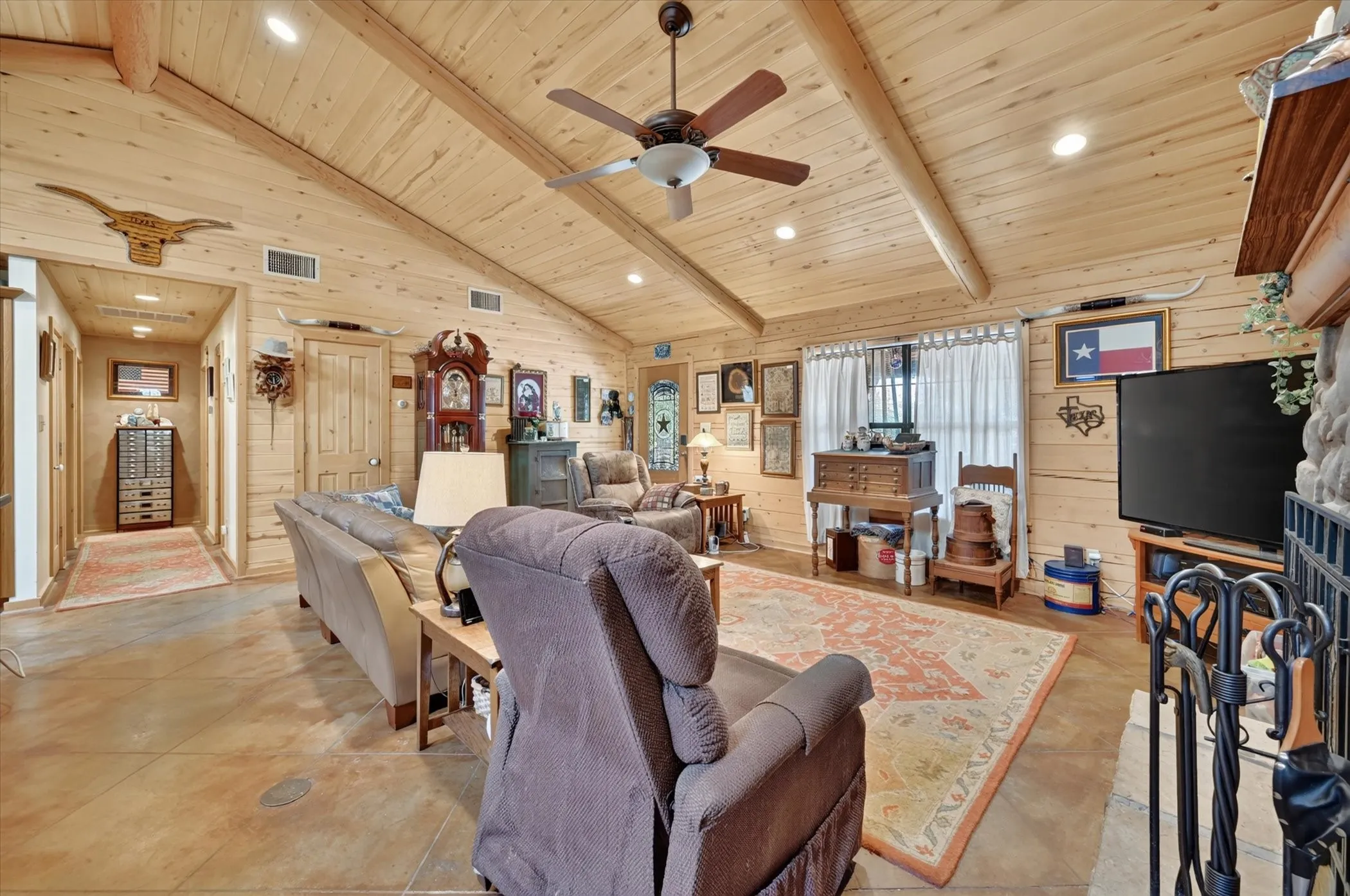 Vaulted wood-paneled ceiling with exposed beams, recessed lighting, and a ceiling fan