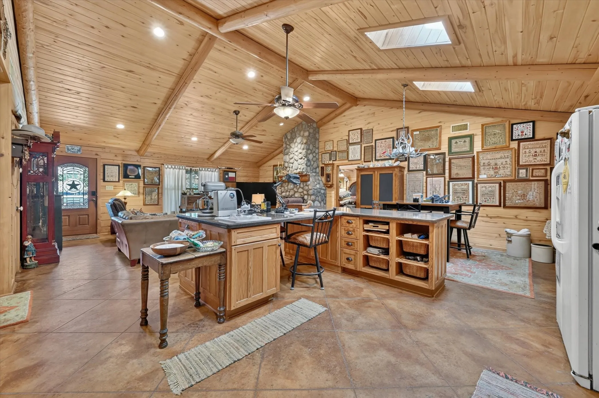 Vaulted wood-paneled ceiling with exposed beams, skylights, recessed lighting, and ceiling fans