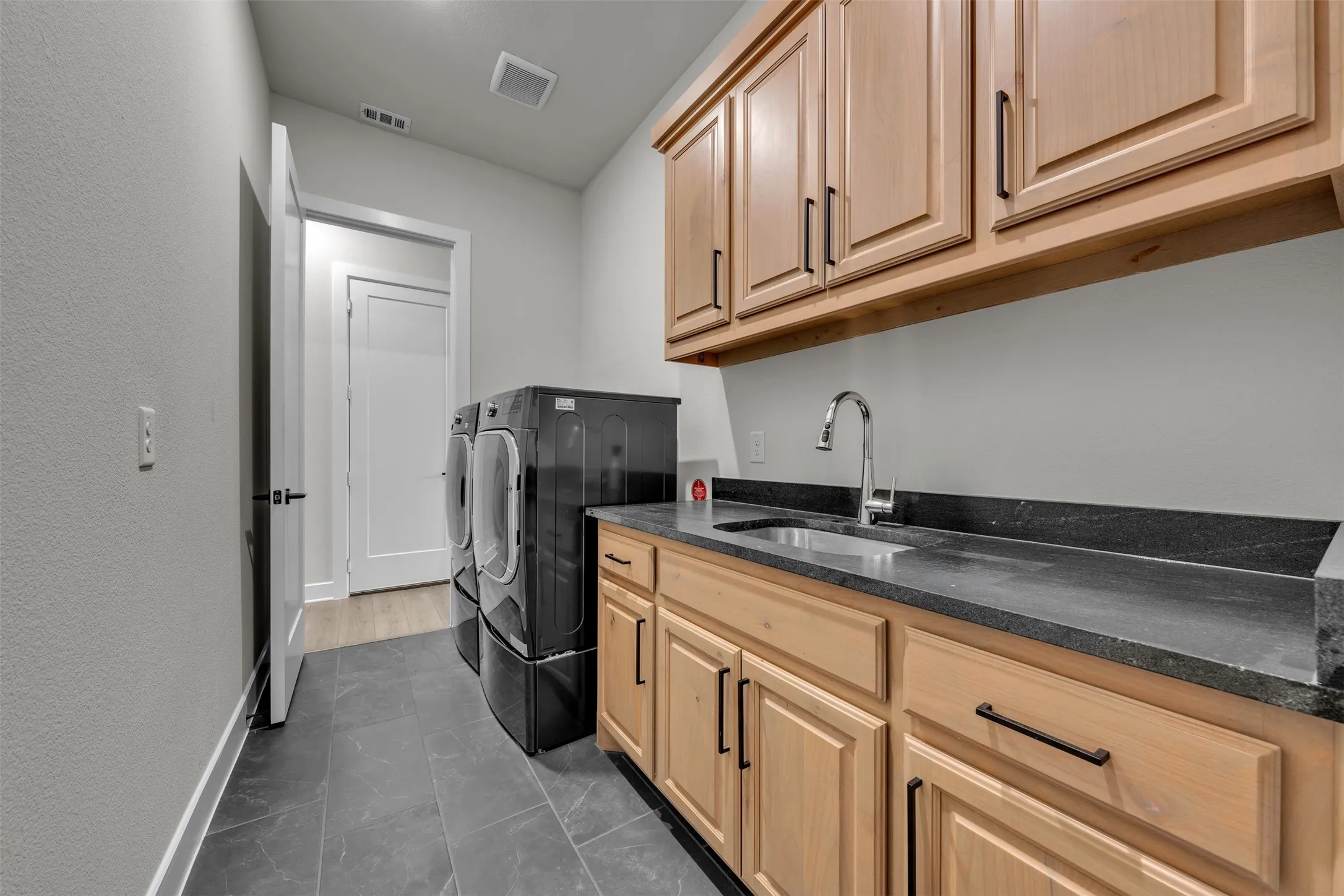 Utility Room. Washer and Dryer Convey. Utility Sink and Cabinets. Opens to Hallway and Primary Closet.