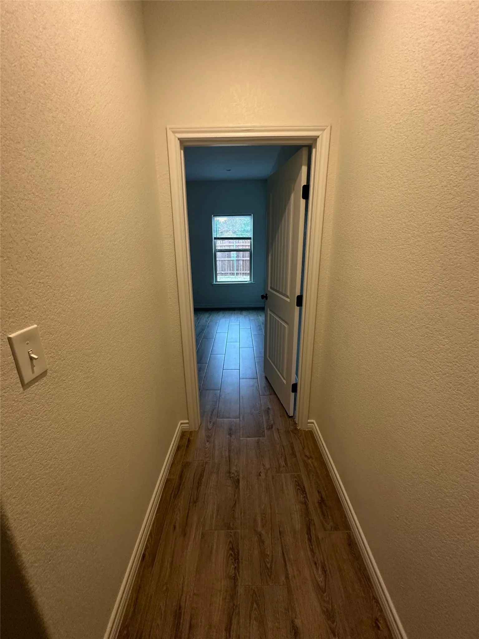 Wood-look tile flooring in a hallway with textured walls and white trim