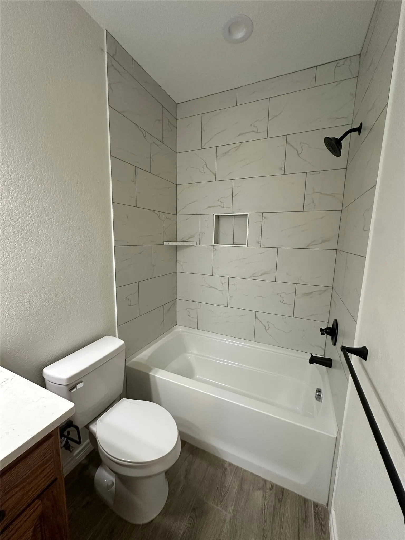 Bathroom featuring a tub/shower combination with tile surround, built-in shower niche, and matte black fixtures